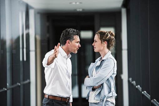 A man and woman pictured arguing in office passageway  |  Photo: Getty Images