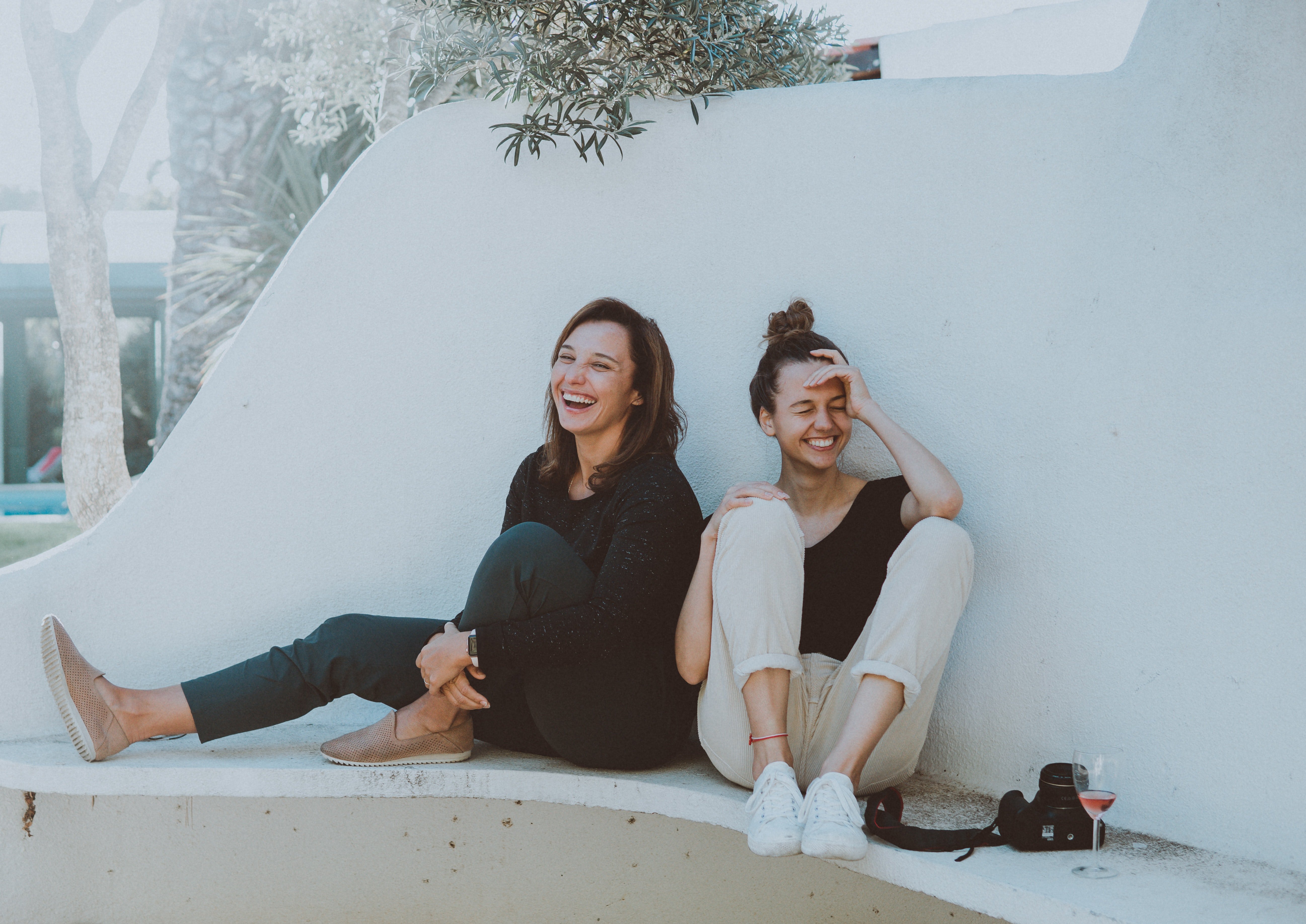 Sisters sitting outdoors, laughing together. | Source: Pexels/Elle Hughes