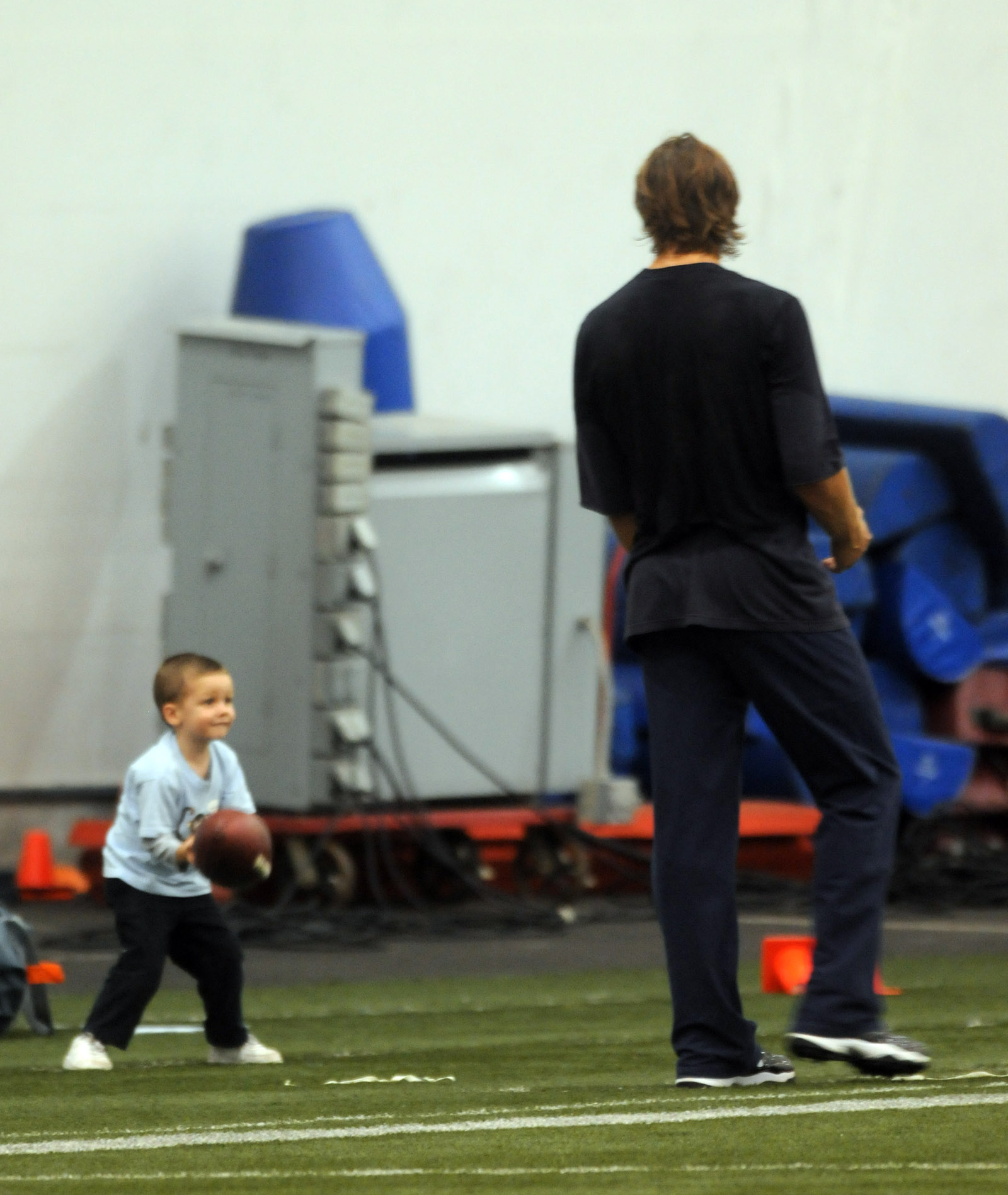 Tom Brady shares a playful moment with young Jack Moynahan at the Dana-Farber Field House, tossing a football back and forth as practice winds down in Foxboro.