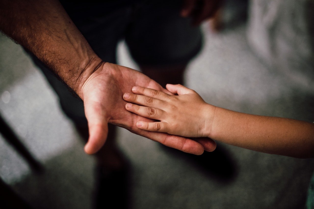 Niño pone su mano sobre la de su padre. | Foto: Pexels