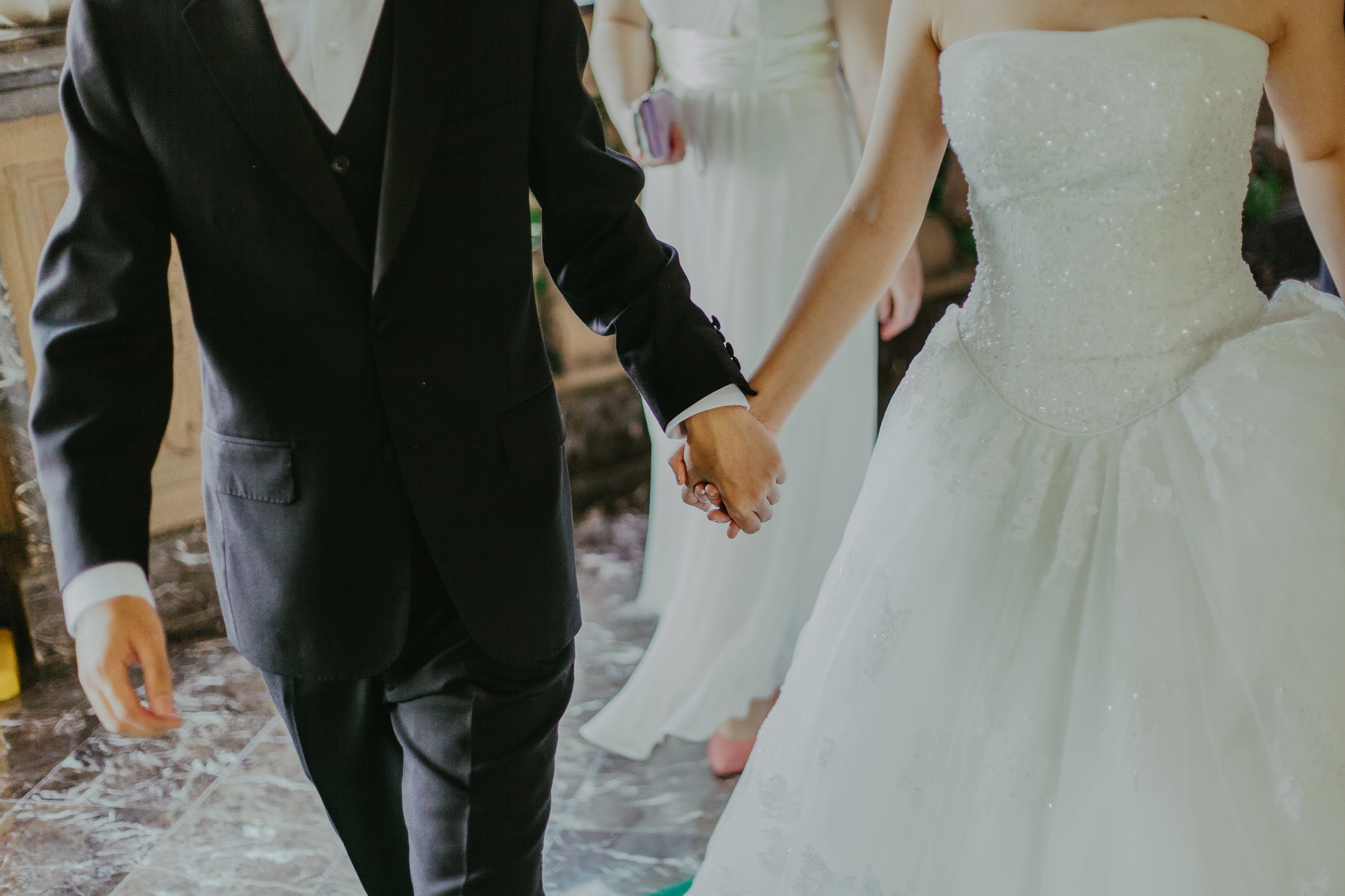 Pareja de novios con sus trajes de boda caminando tomados de las manos. | Foto: Pexels