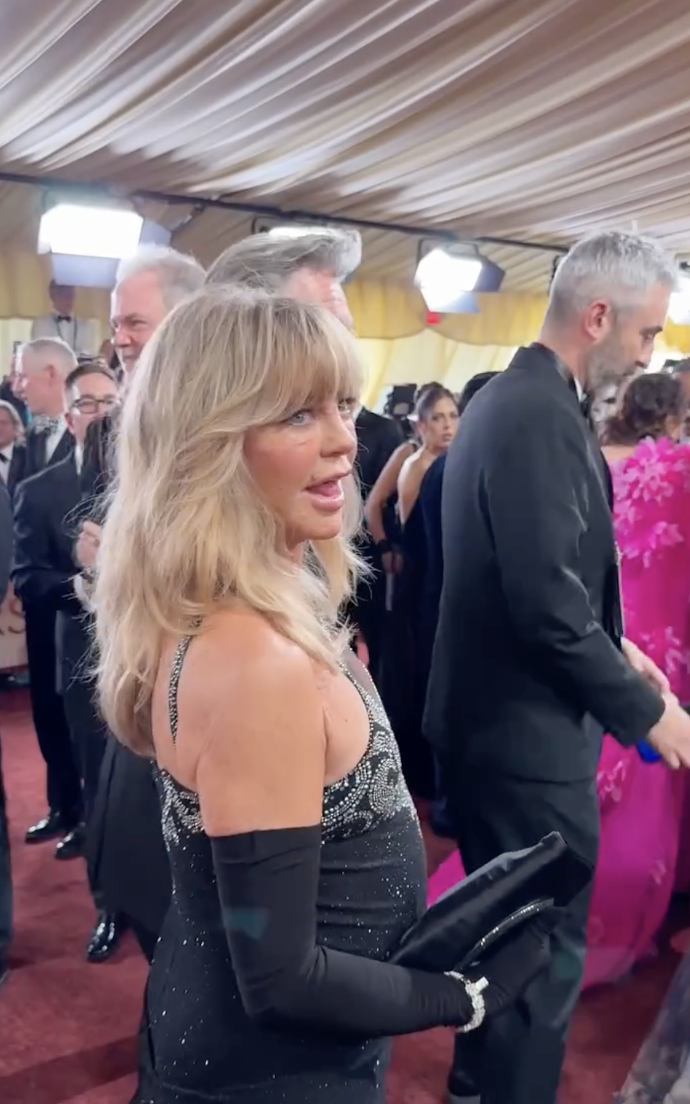 Goldie Hawn turns toward the cameras, briefly sticking out her tongue as photographers capture the moment on the busy red carpet. | Source: Instagram/enews