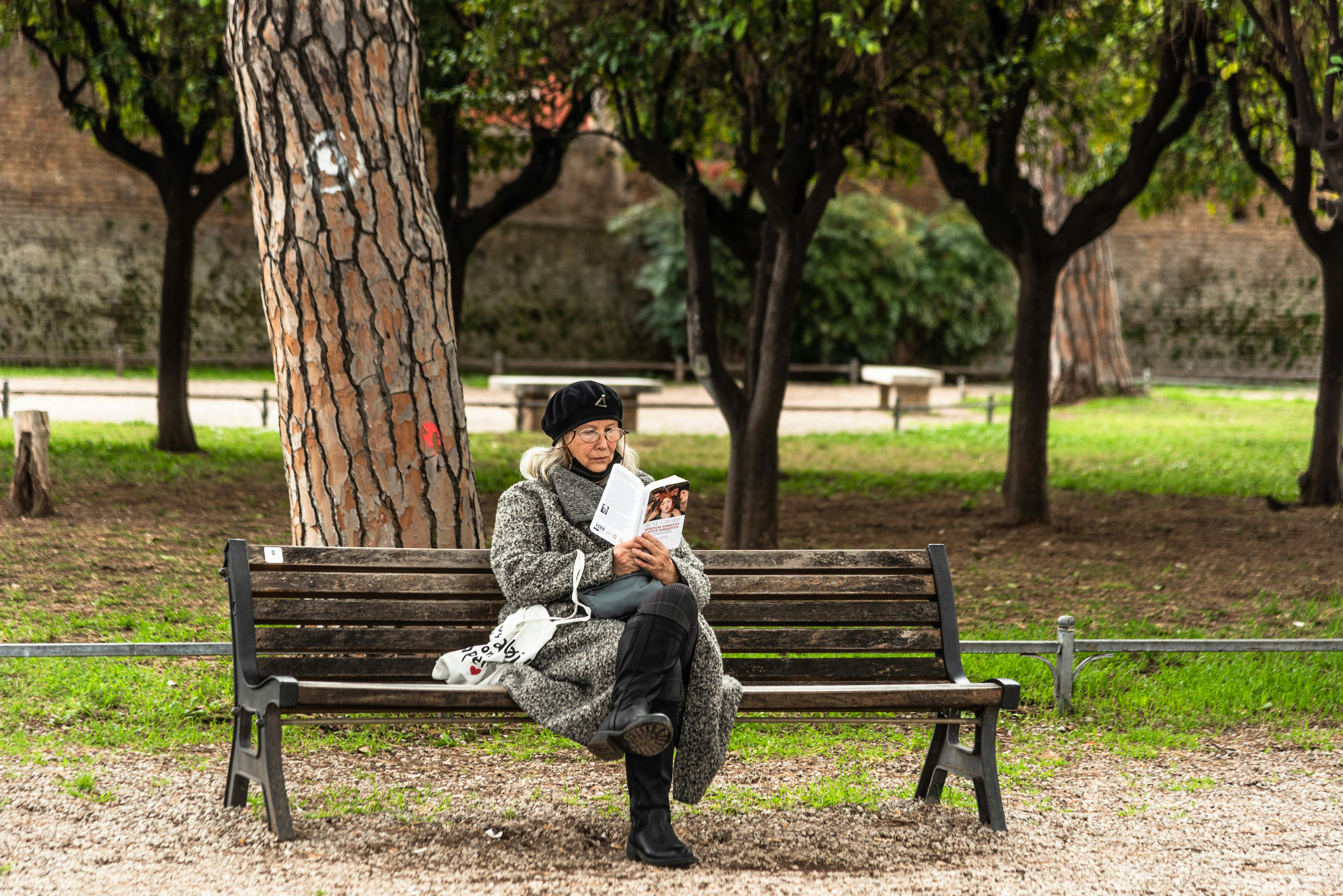 A woman reading a book while sitting on a park bench | Source: Pexels