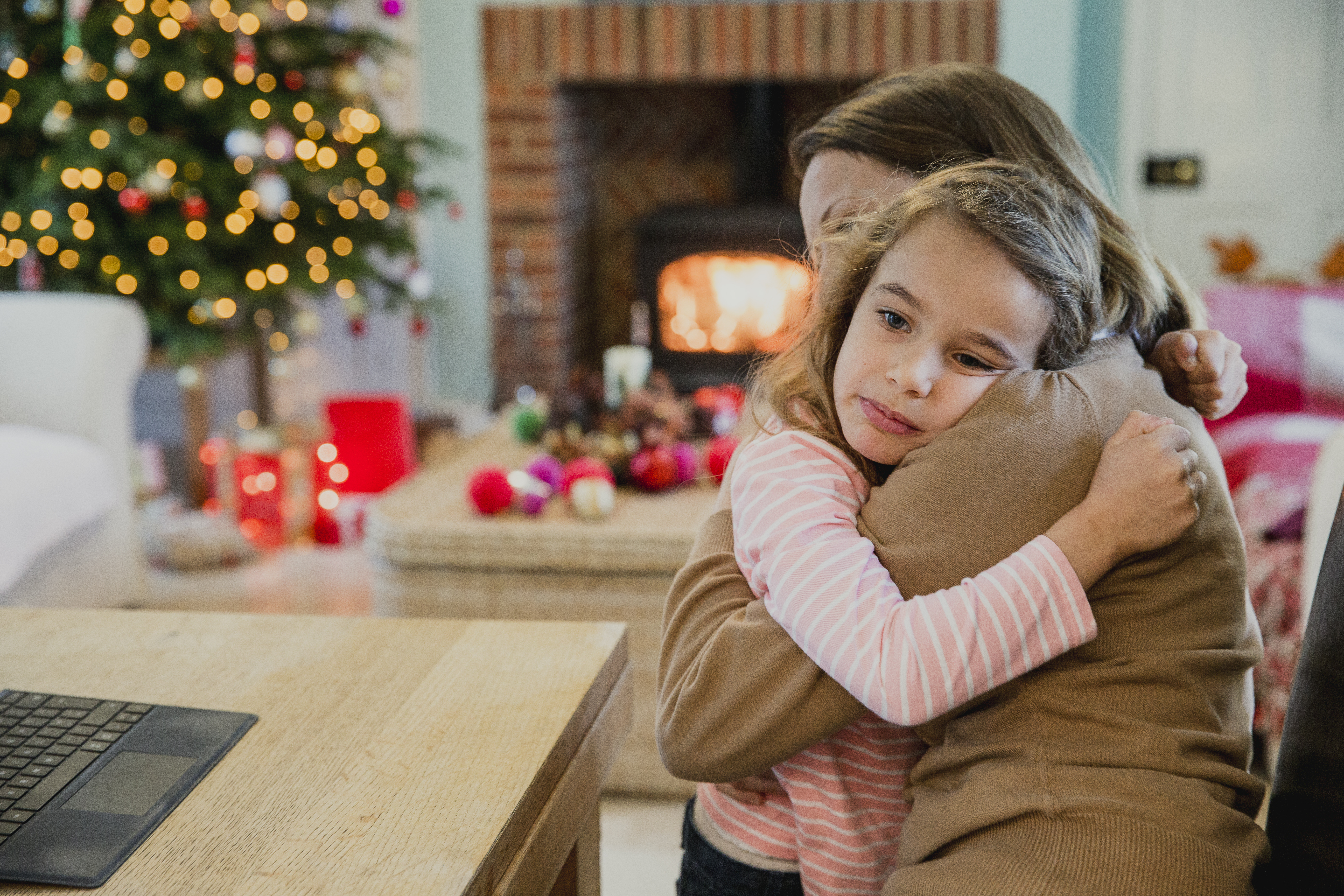 A sad young girl hugging her mom at Christmas | Source: Getty Images