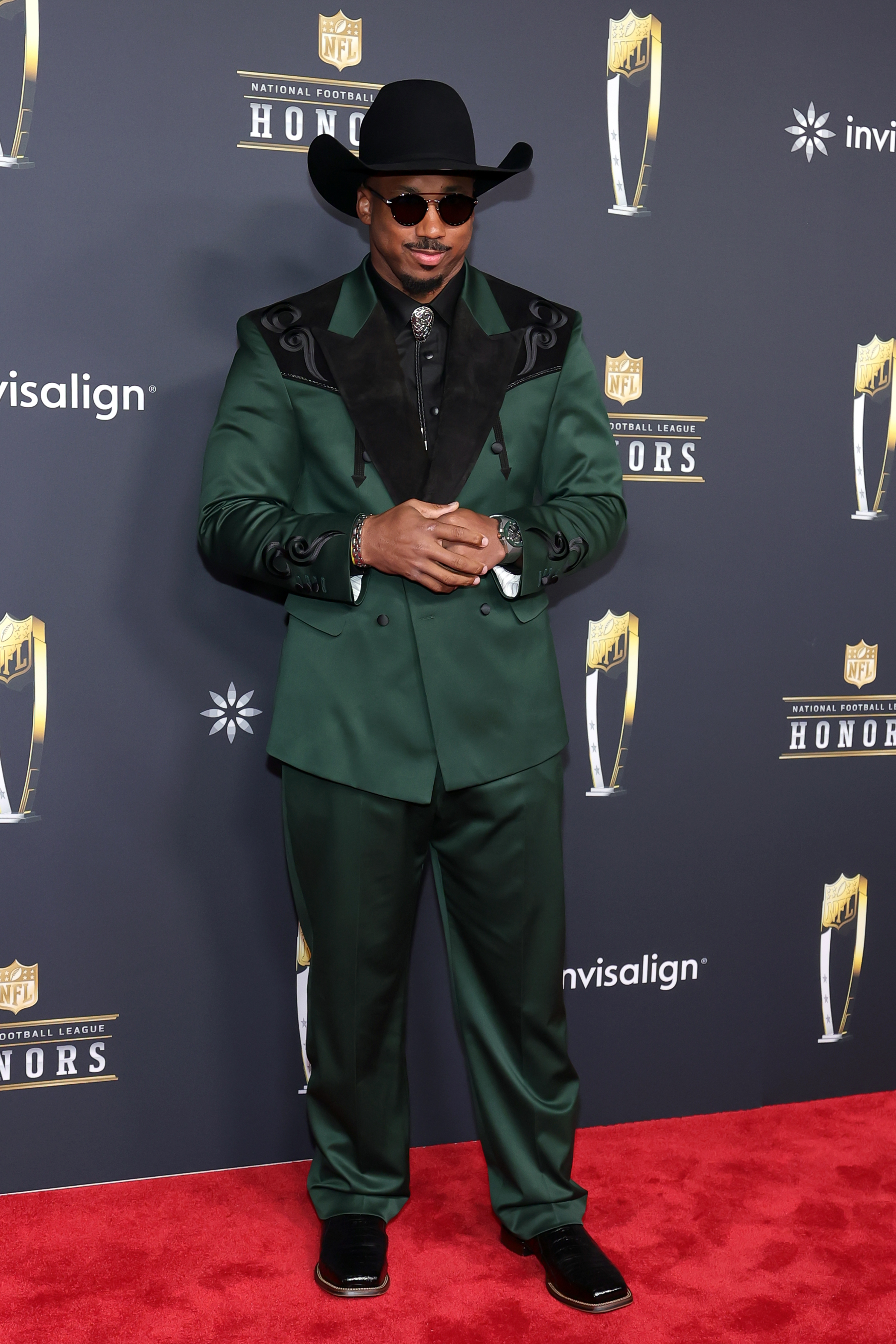 Myles Garrett makes a statement in a dark green suit with Western-inspired accents and a black cowboy hat, blending fashion-forward flair with his confident presence.