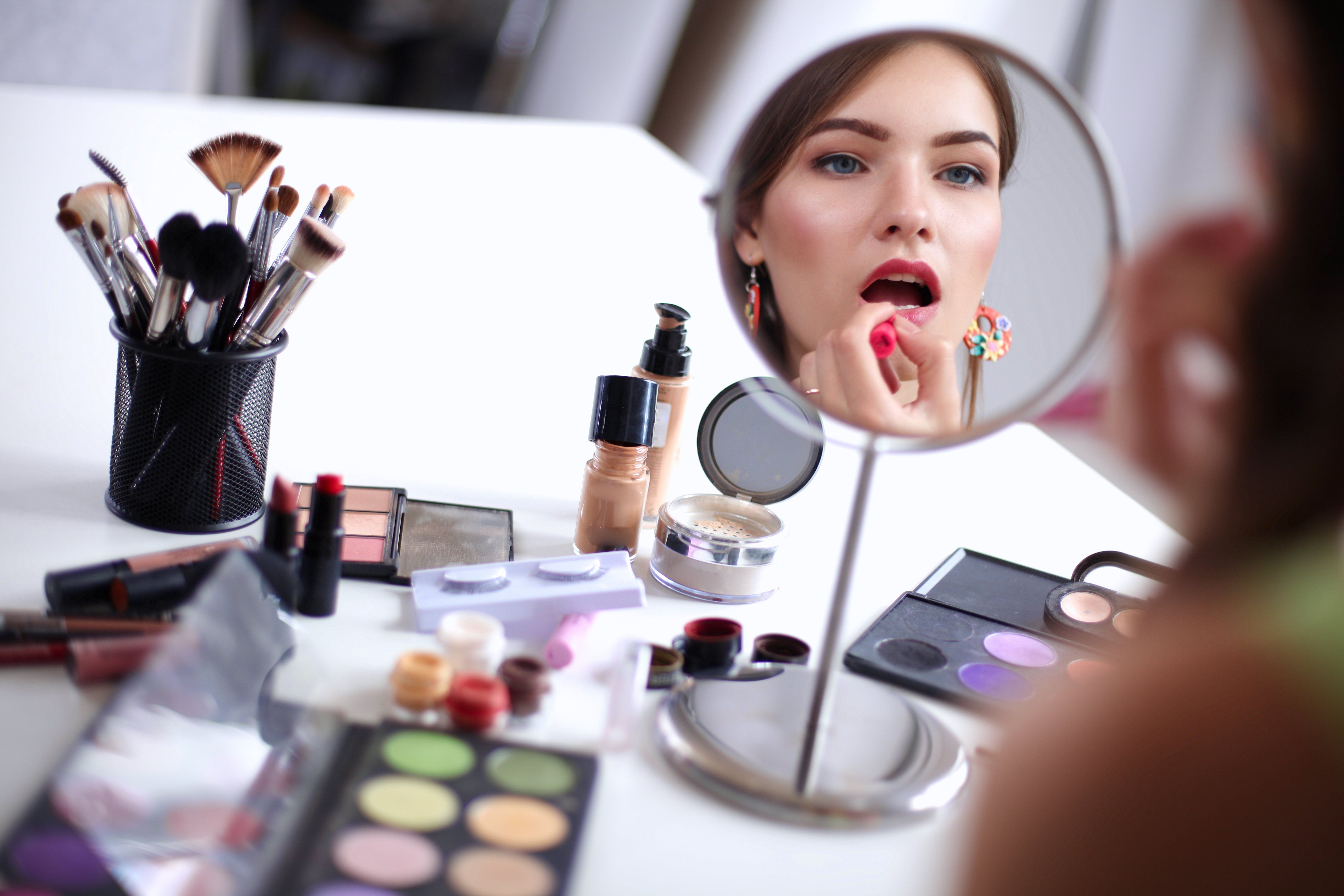 Une belle femme se maquillant près d'un miroir. | Photo : Shutterstock