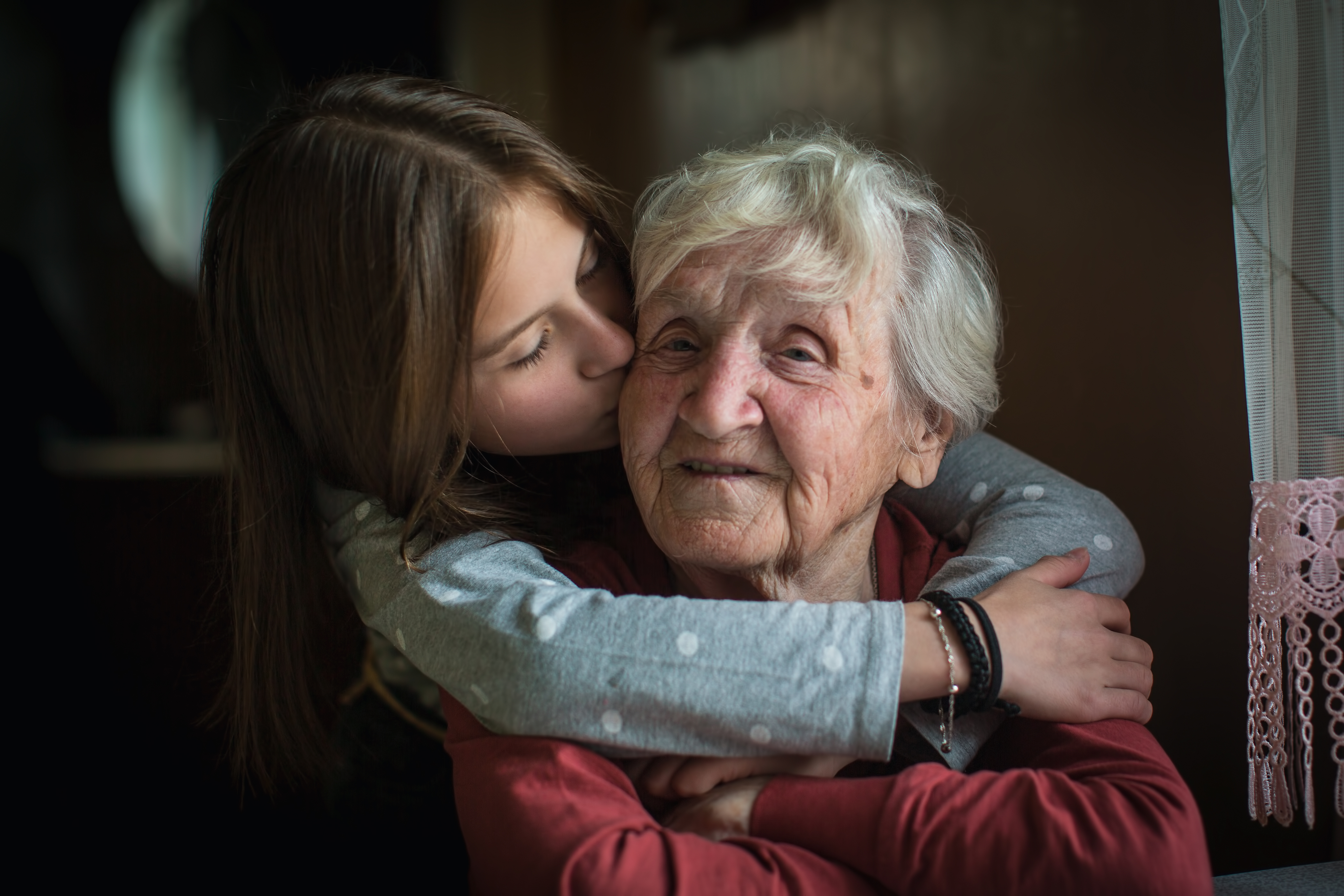 A woman kisses her grandmother on the cheek | Source: Shutterstock