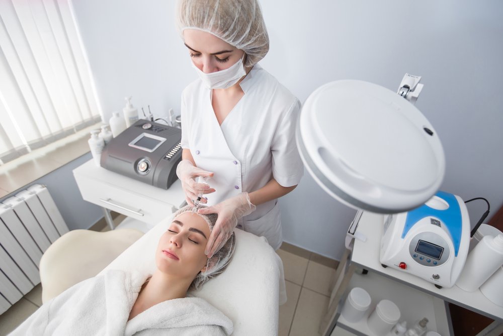 Mujer recostada recibiendo aplicación de bótox en la frente. | Foto: Shutterstock