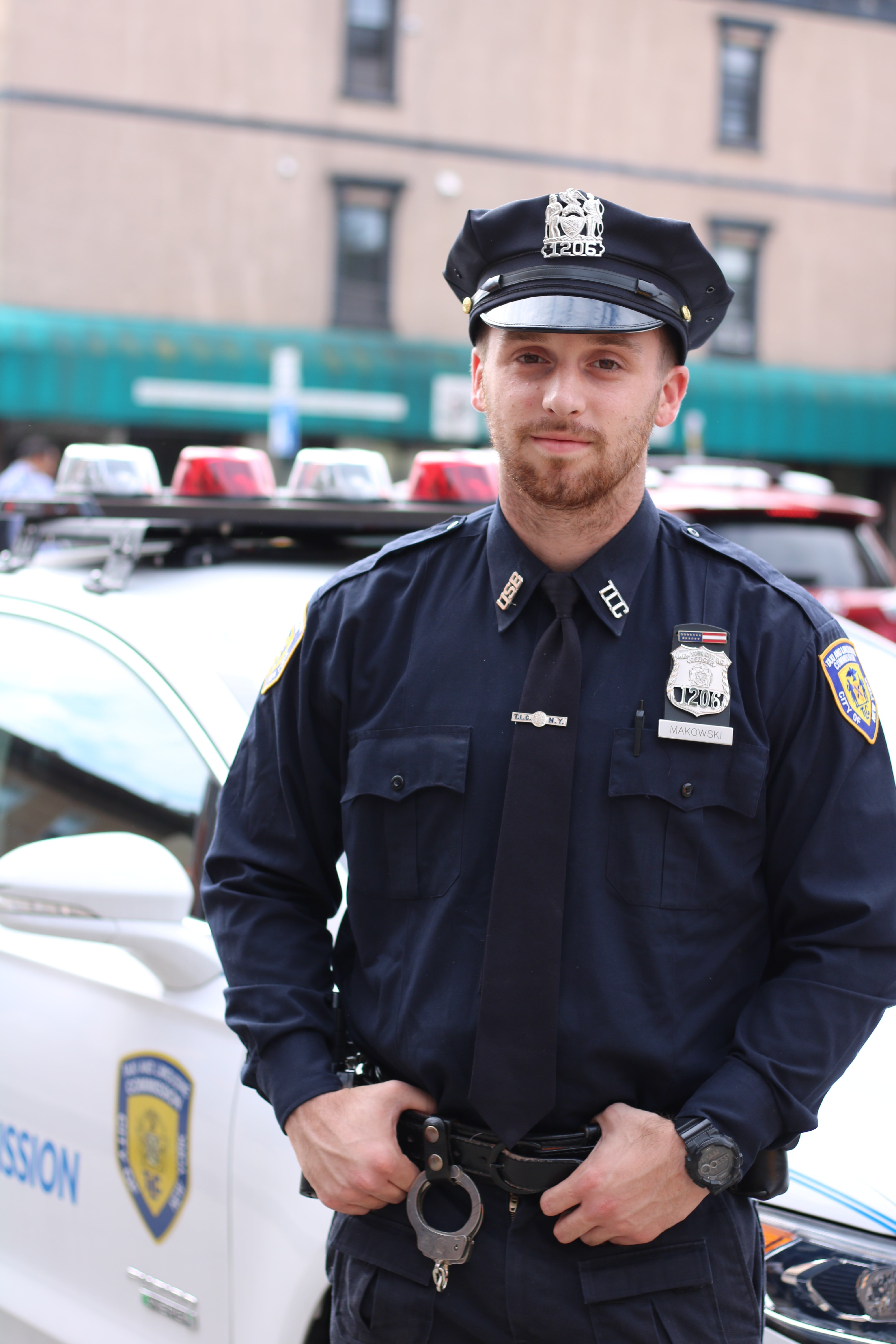 Oficial de policía cerca de un vehículo patrulla. | Foto: Pexels