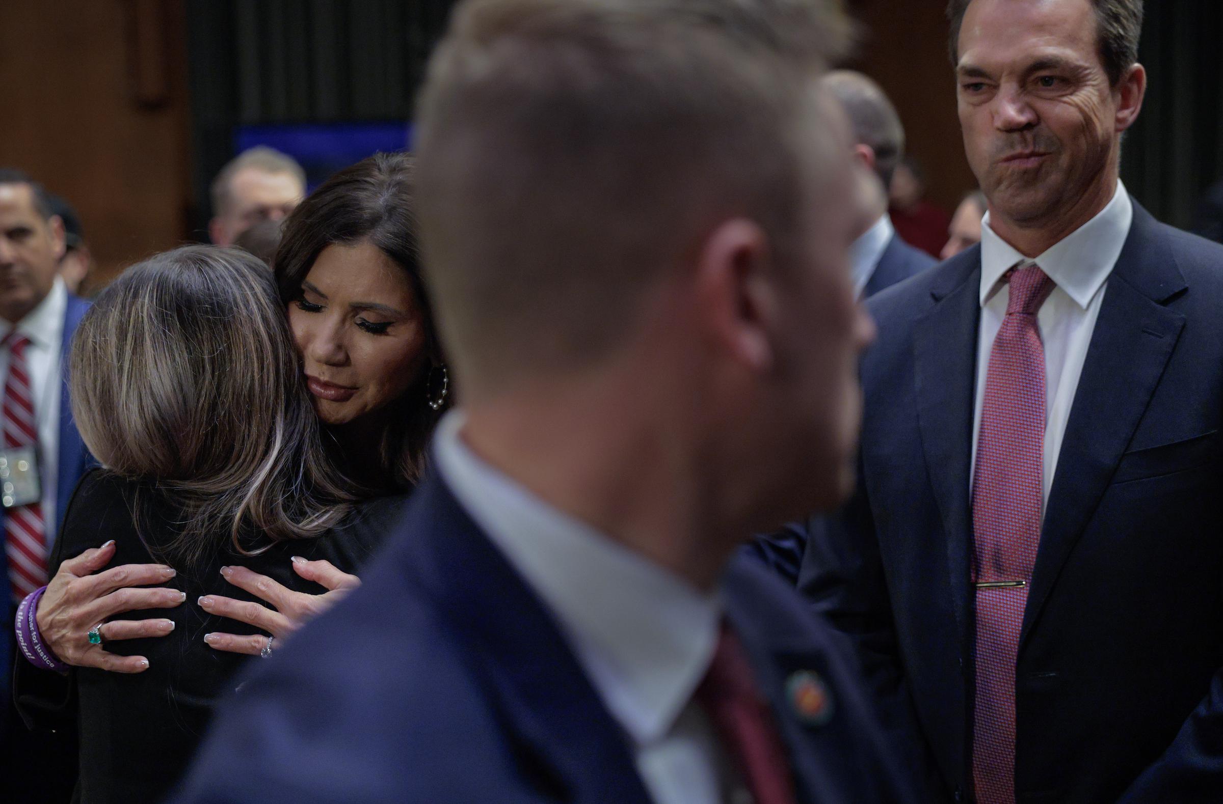 Kristi Noem embraces a supporter as her husband, Bryon Noem, stands by after testifying before the Senate Judiciary Committee at the Dirksen Senate Office Building on March 3, 2026, in Washington, D.C. | Source: Getty Images