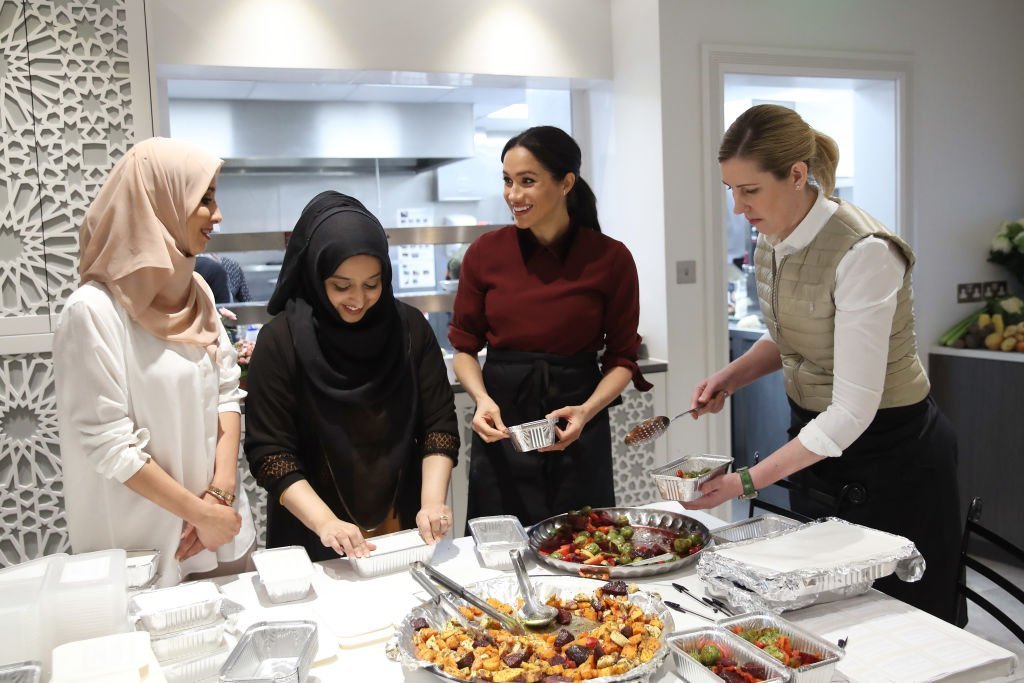 Meghan, Duchess of Sussex with chef Clare Smyth (R) and kitchen co-ordinator Zaheera Sufyaan (2L) as she visits the Hubb Community Kitchen. | Photo: Getty Images