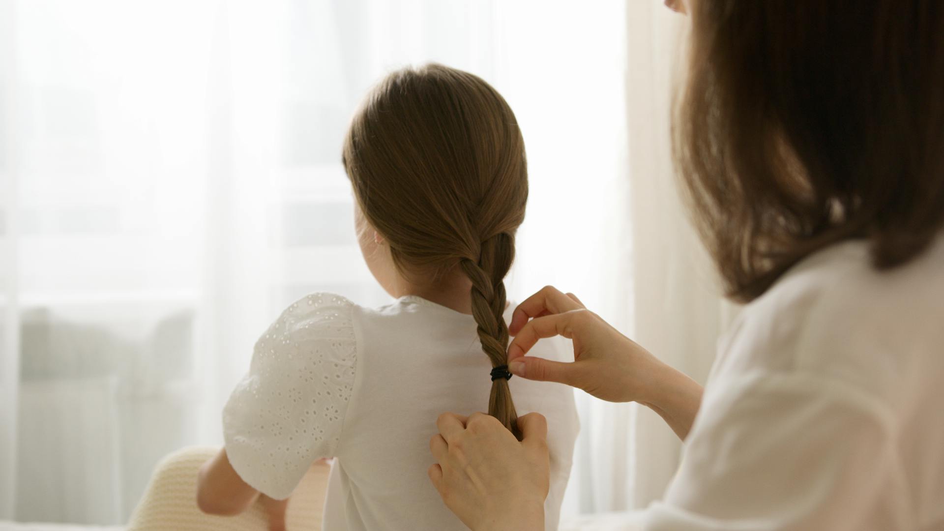 A woman braiding a little girl's hair | Source: Pexels