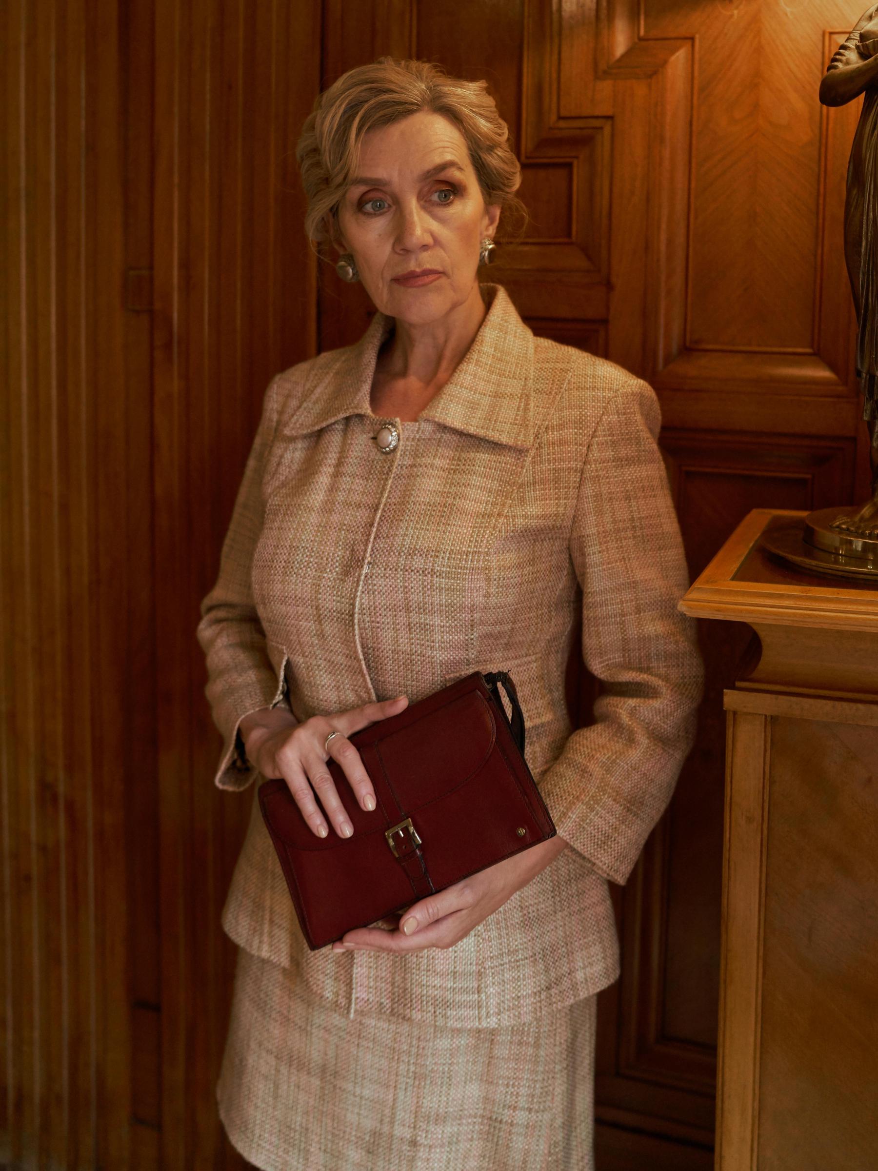 An elegantly-dressed woman standing in a hallway | Source: Pexels