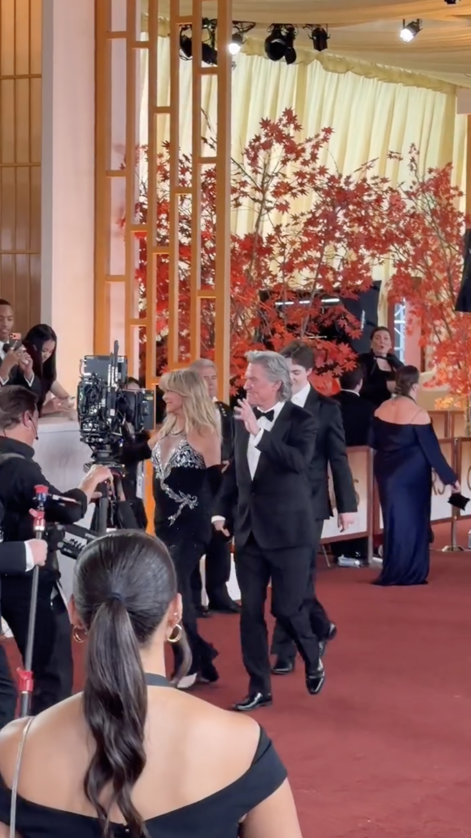 Goldie Hawn and Kurt Russell pass a camera crew filming the arrivals, offering a behind-the-scenes glimpse of the busy Oscars red carpet atmosphere. | Source: Instagram/enews