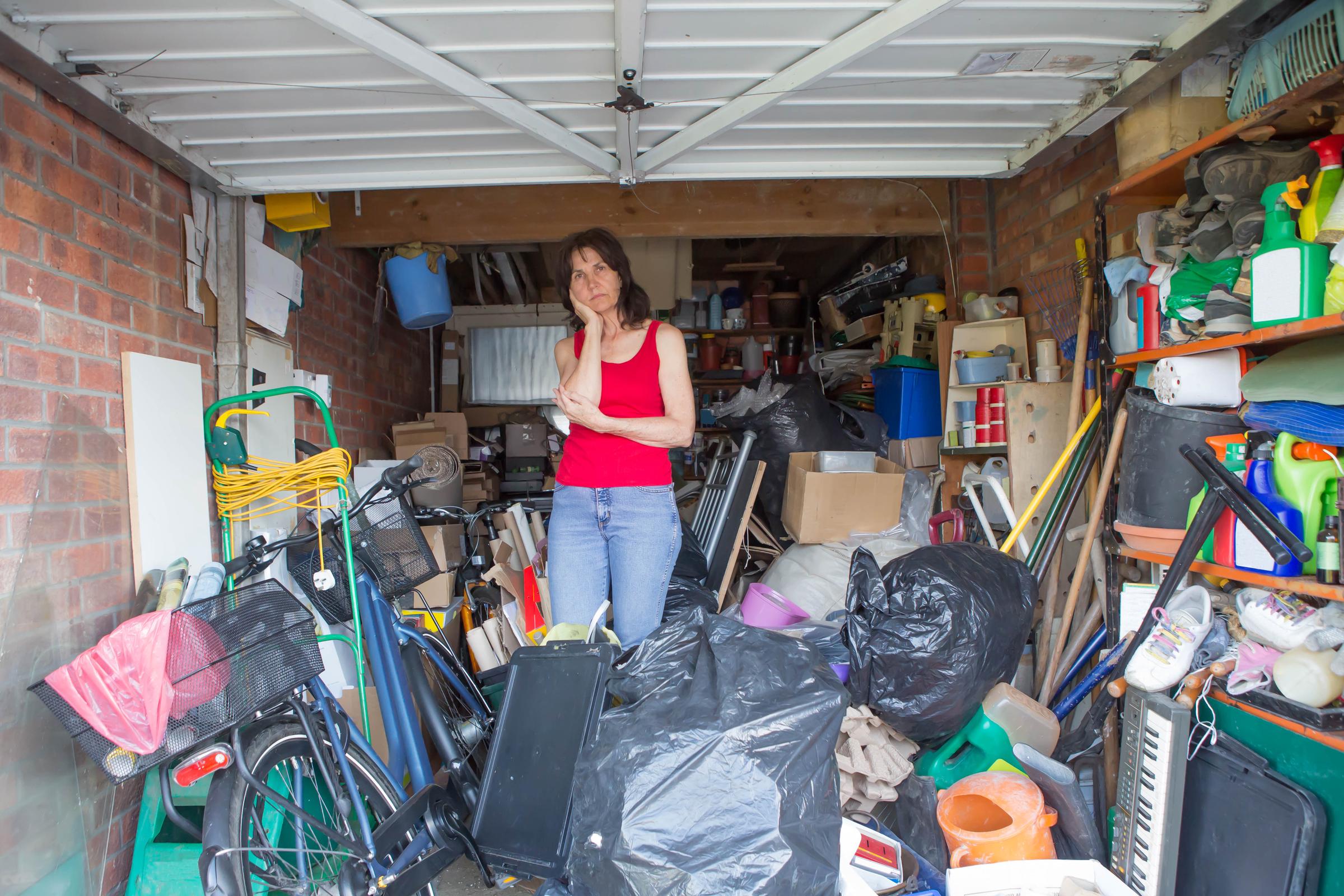 Woman standing in the middle of her garage surrounded by clutter | Source:  Shutterstock
