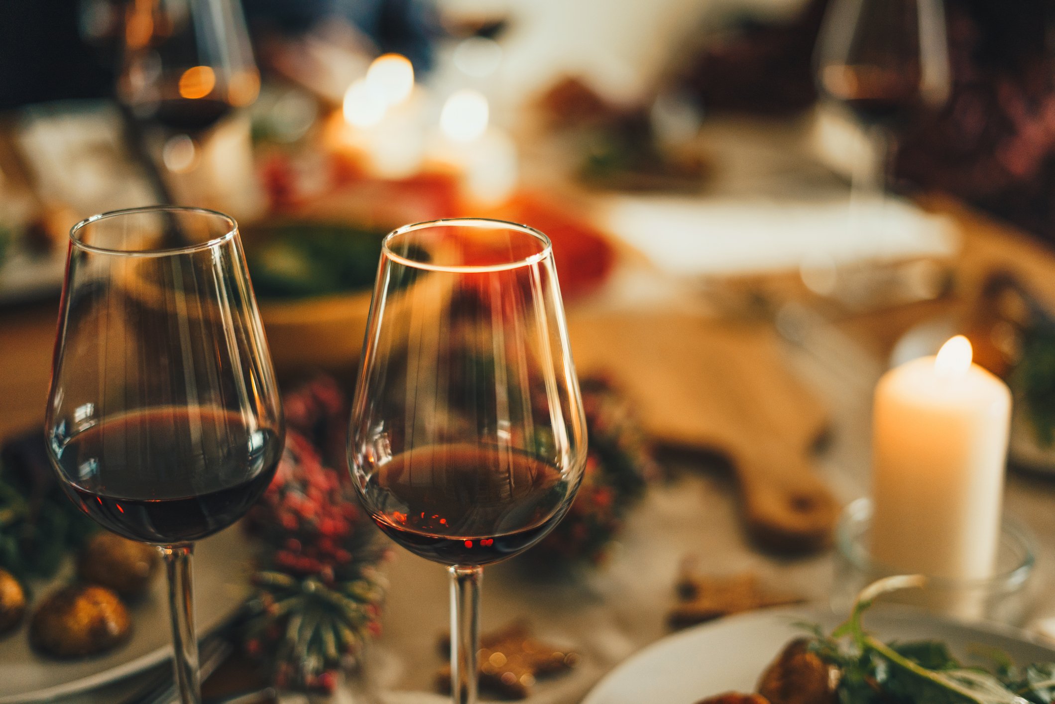 A close up shot of red wine glasses at Christmas dinner table. | Photo: Getty Images