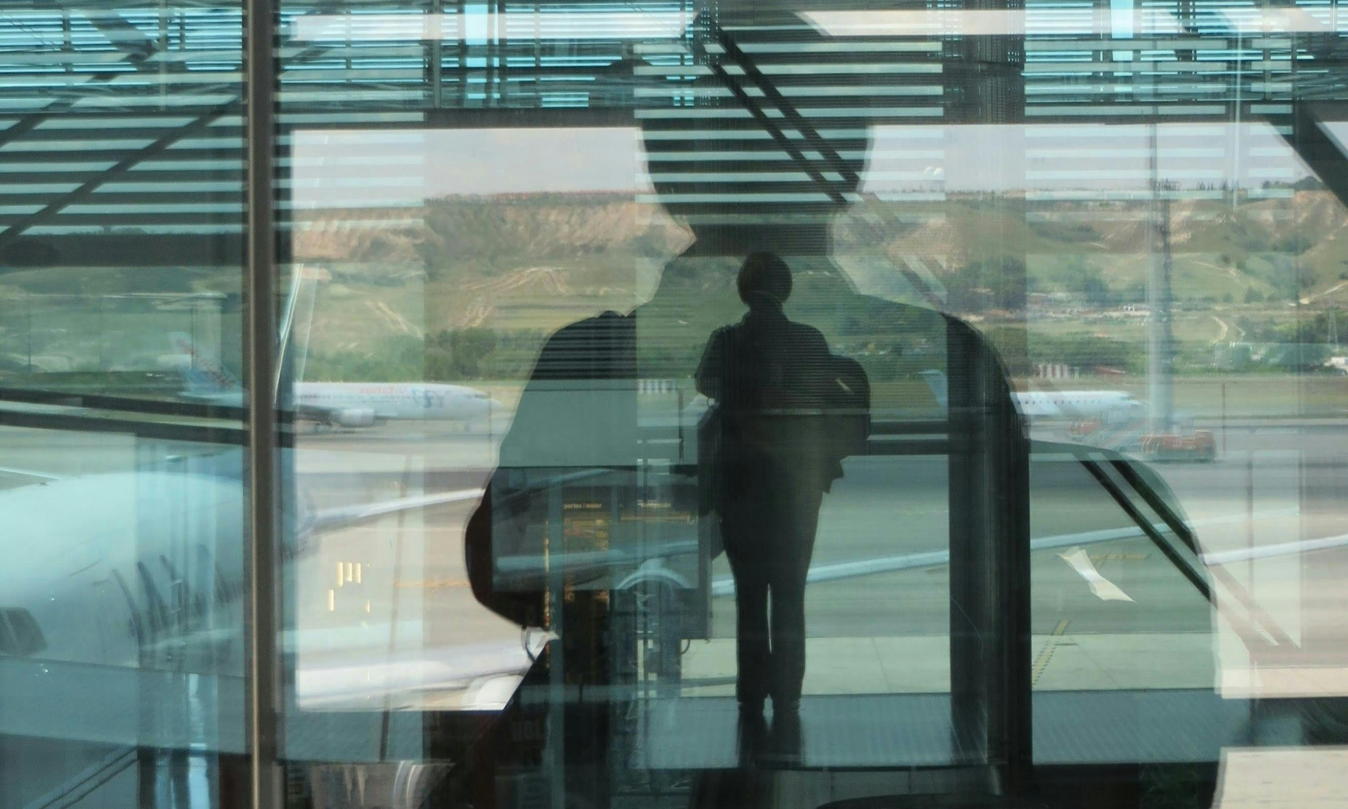 Sarah's reflection in window glass as she waits at the airport | Source: Pexels