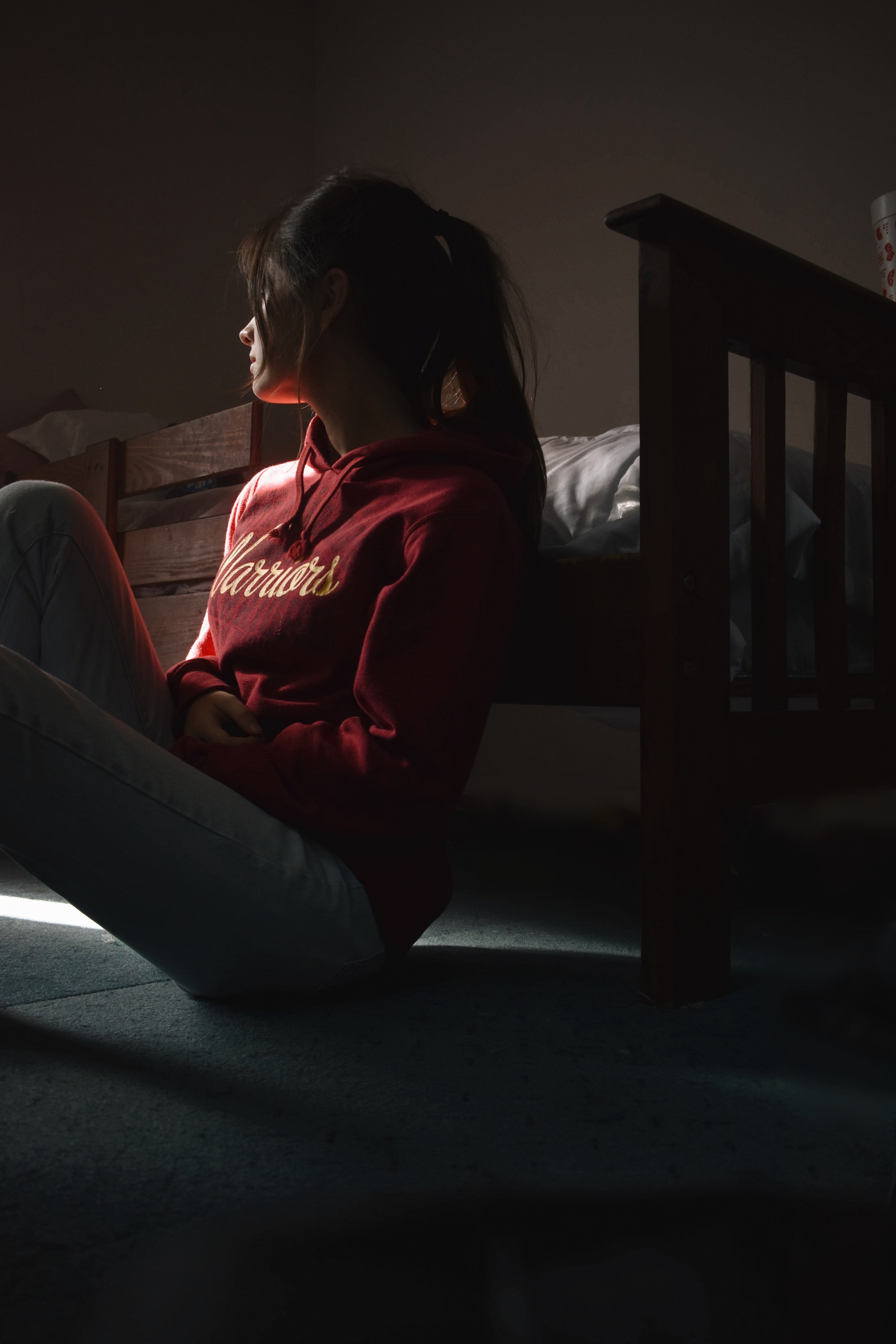 Sad woman sitting on the floor by a bed | Source: Pexels