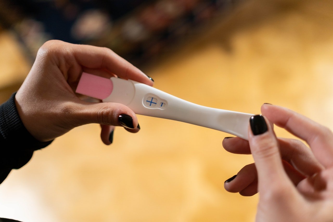 The girl holding positive pregnancy strip test | Source: Pexels