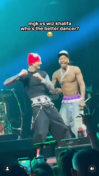 MGK and Wiz Khalifa share a laugh as they square off during a playful dance battle onstage in Charlotte, North Carolina, in a video shared on June 1, 2026. The friendly showdown unfolded during the closing moments of "Girl Next Door" while the rappers were performing together on the "Lost Americana Tour." | Source: Instagram/mgkmagic