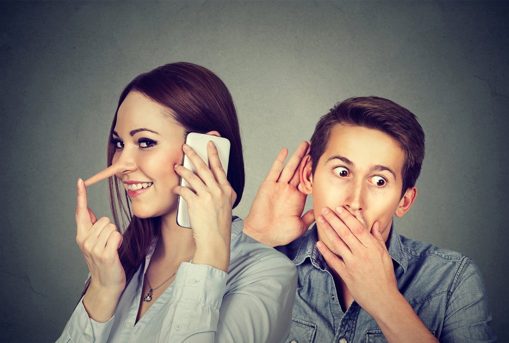 Hombre espiando la conversación de su novia mentirosa. | Foto: Shutterstock