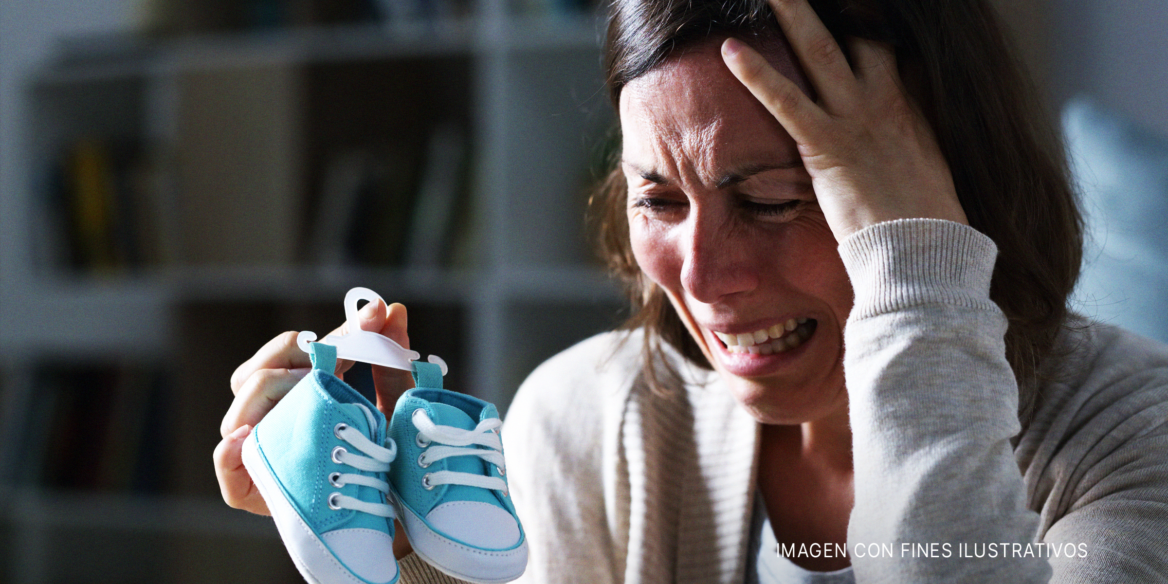 Mujer llora mientras sostiene unos zapatos de bebé | Foto: Shutterstock