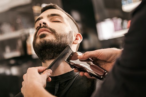 A barber trimming a client's beard / Photo: Getty Images