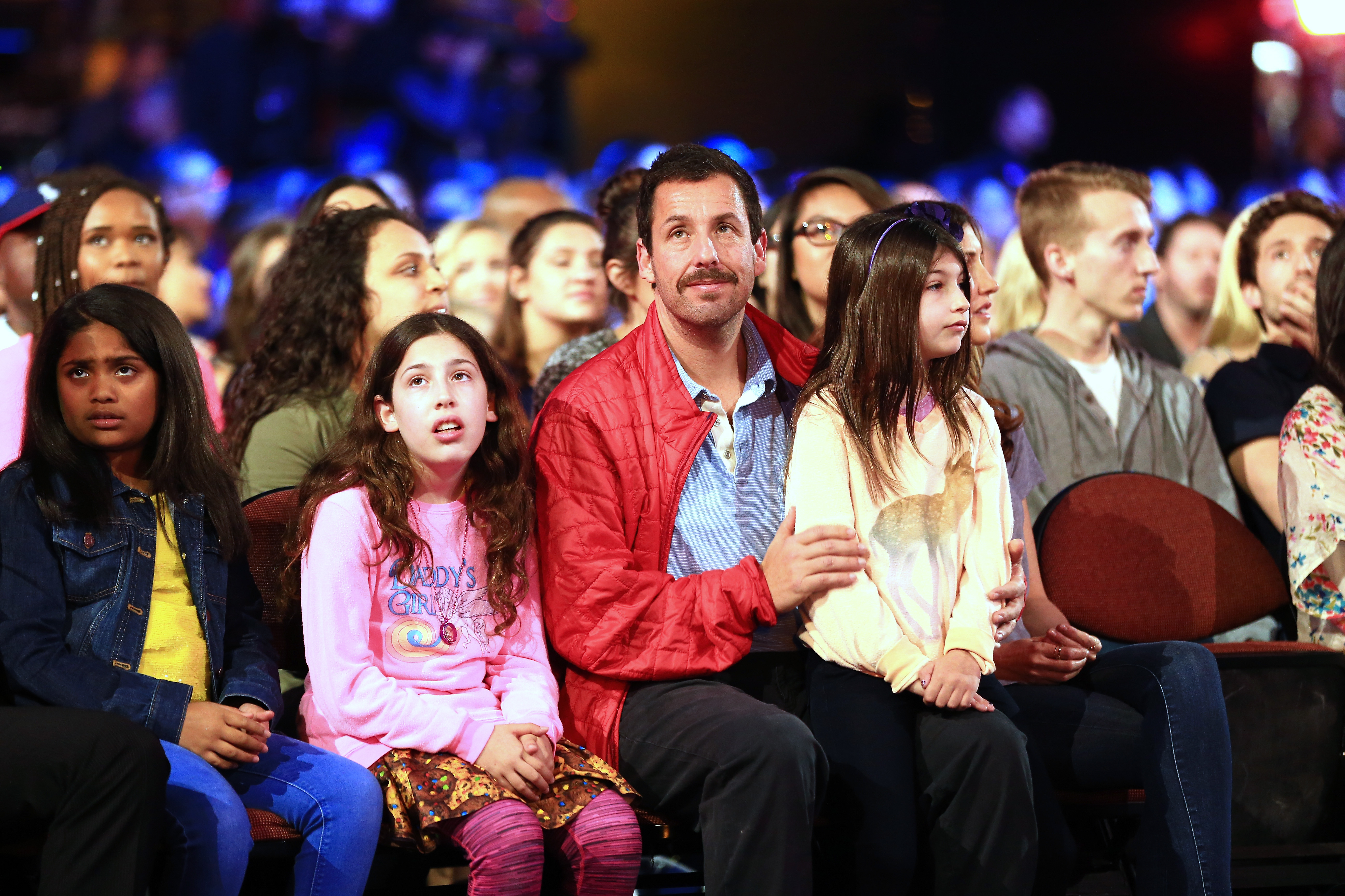At Nickelodeon’s Kids’ Choice Awards in Inglewood, Adam Sandler sat with his daughters, Sadie by his side and Sunny in his arms. All three looked ahead with the same calm focus, their striking resemblance shining through in the shared expressions on their faces.