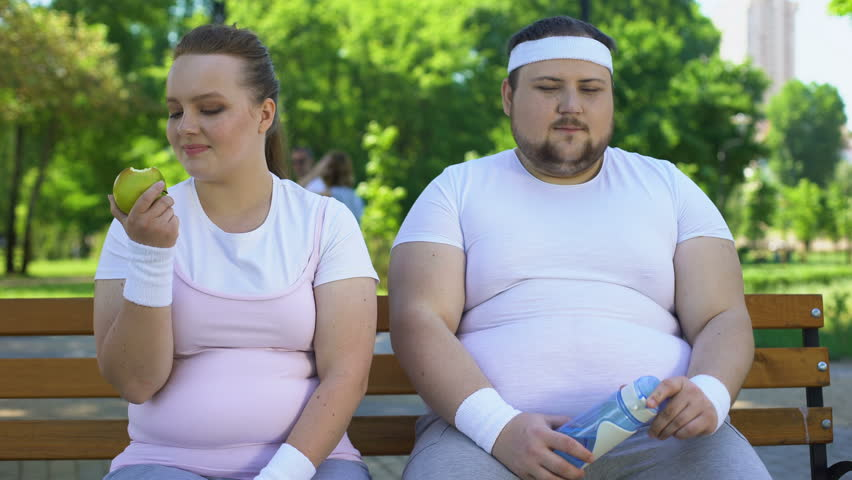 Photo of an overweight couple sitting on a bench | Source: Shutterstock.com