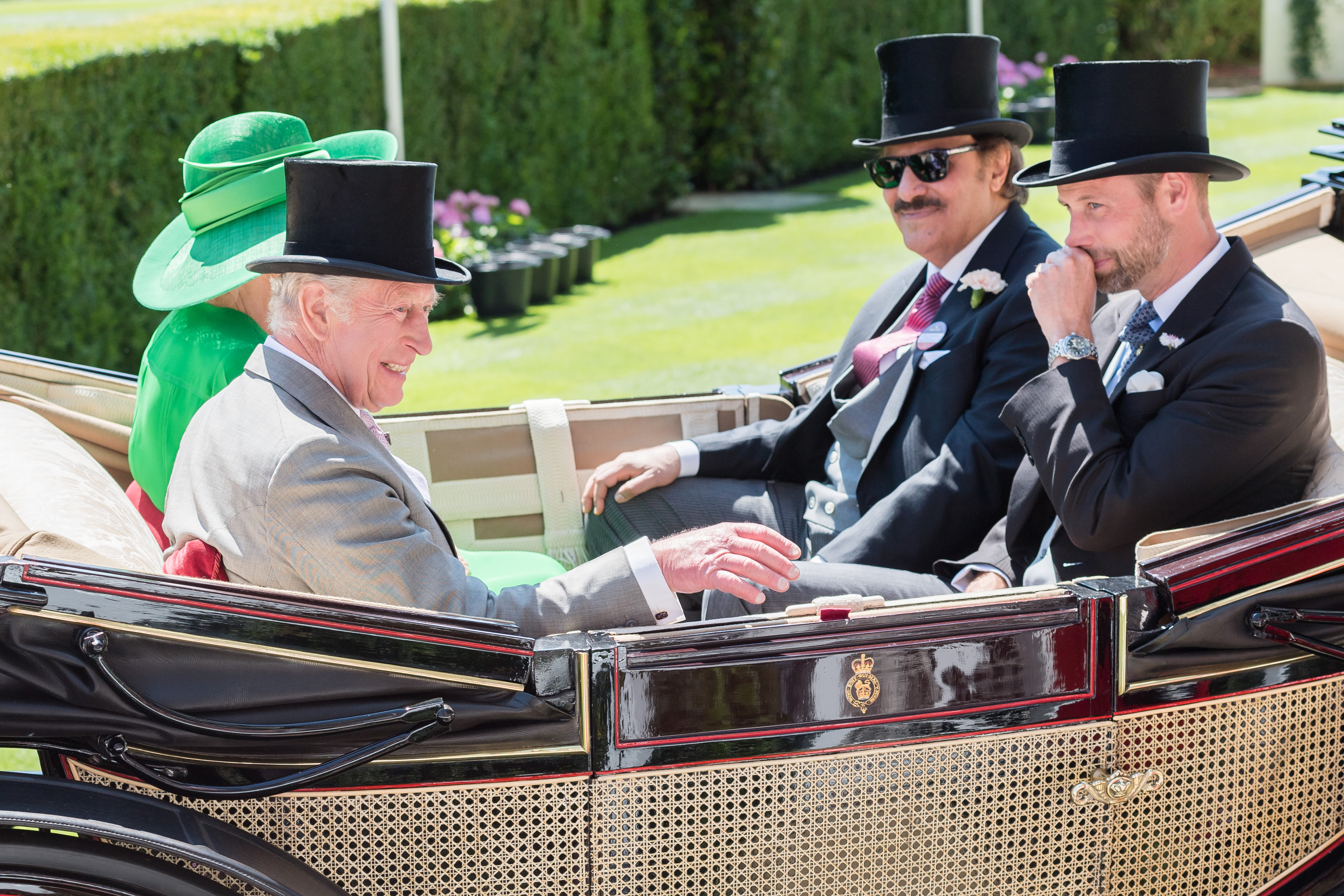 King Charles III shares a laugh while Prince William appears thoughtful, covering his mouth with his hand, as they ride alongside Queen Camilla and Prince Saud bin Khalid Al-Saud in a royal carriage at Royal Ascot on June 18, 2025.