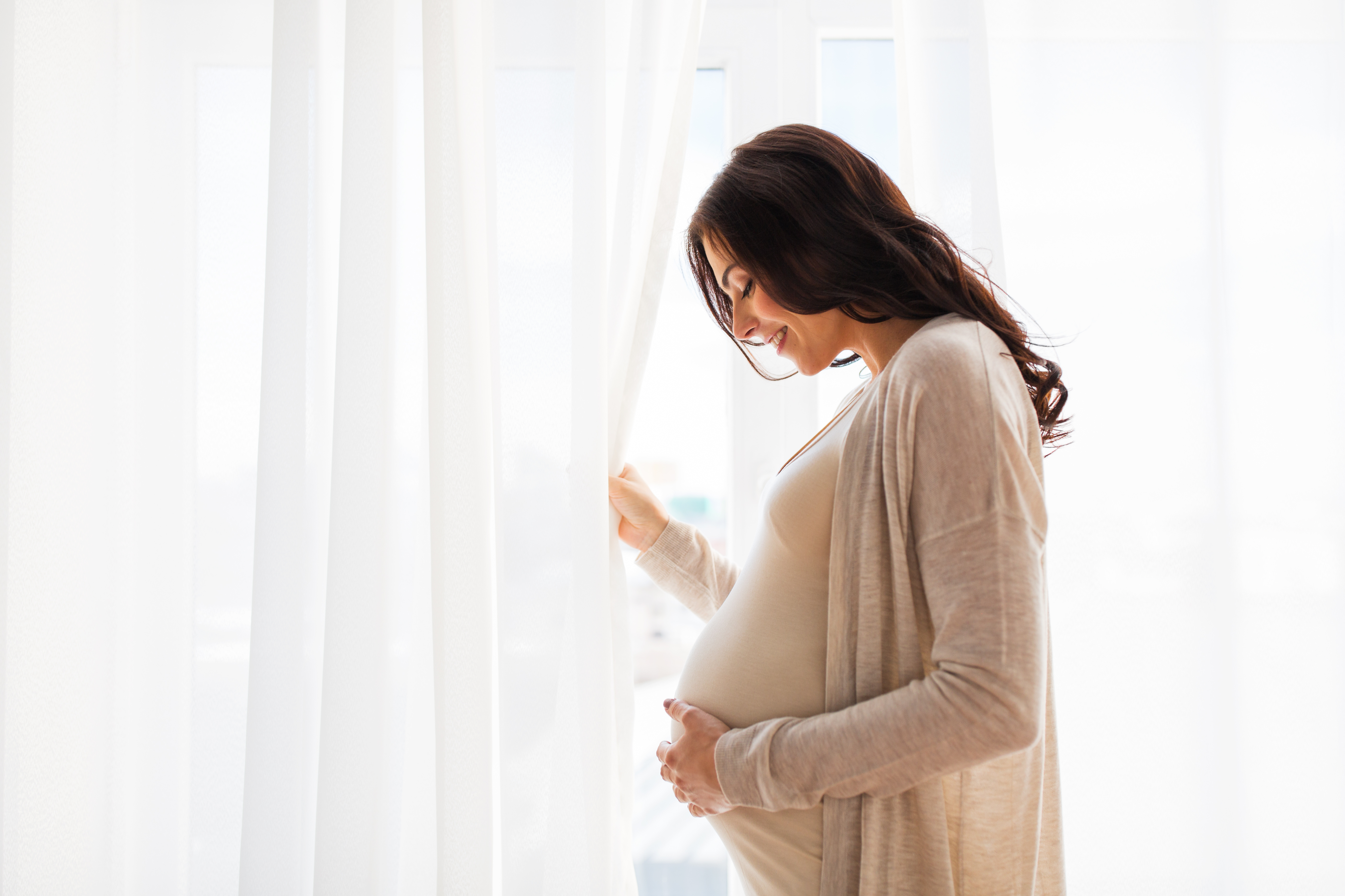 A pregnant woman standing near a window | Source: Shutterstock