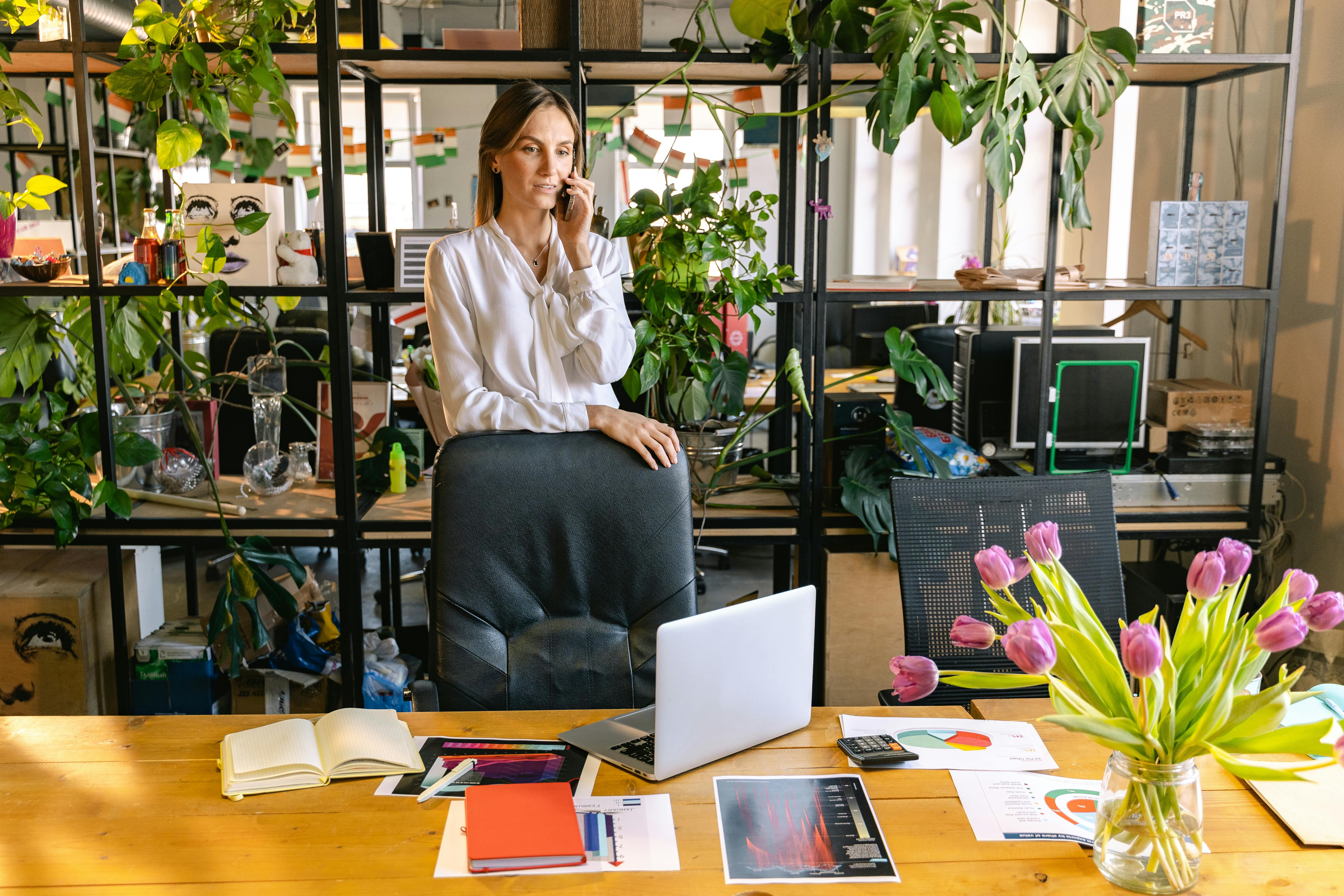 A woman talking on the phone in her office | Source: Pexels