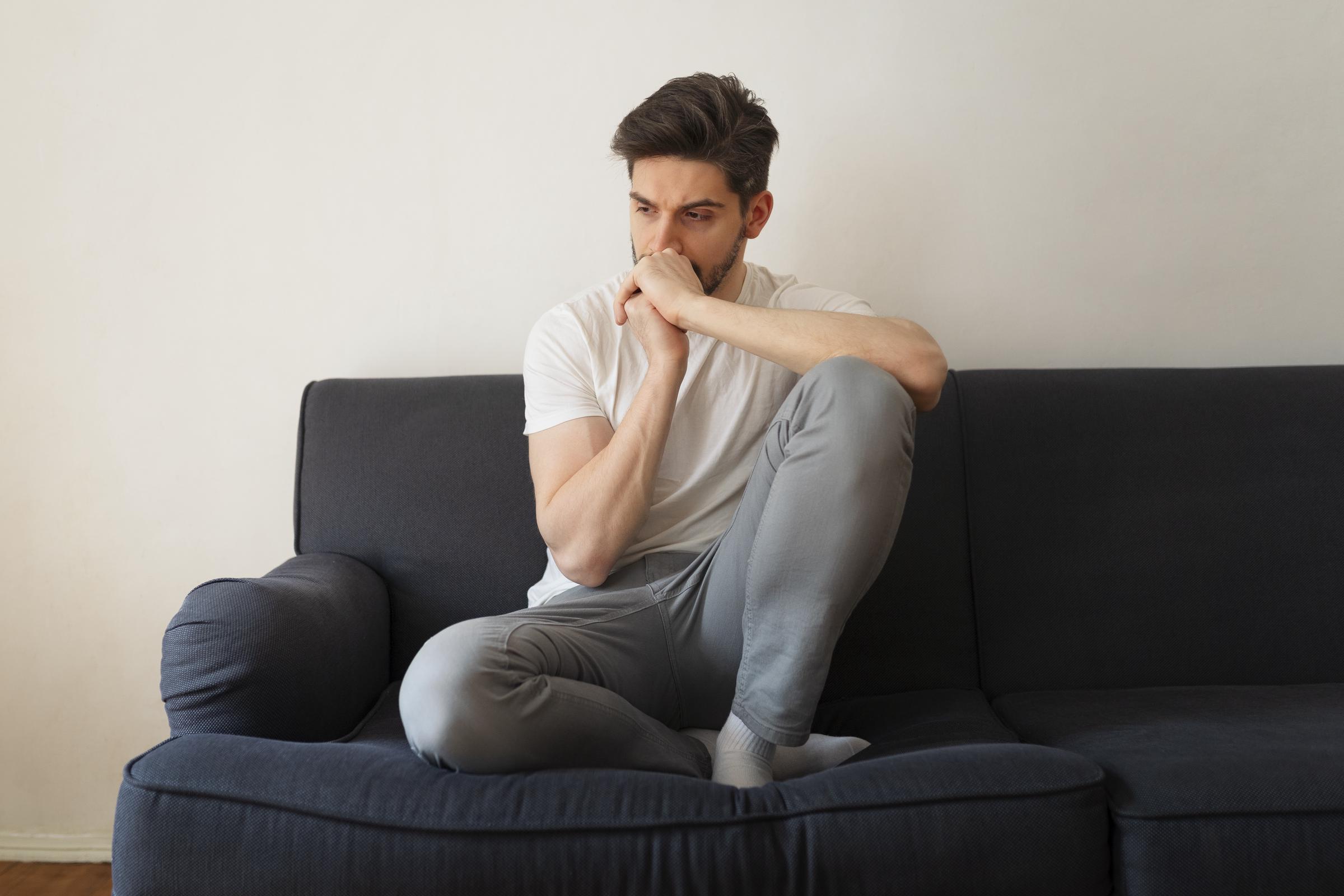 A worried man sitting on a couch | Source: Freepik