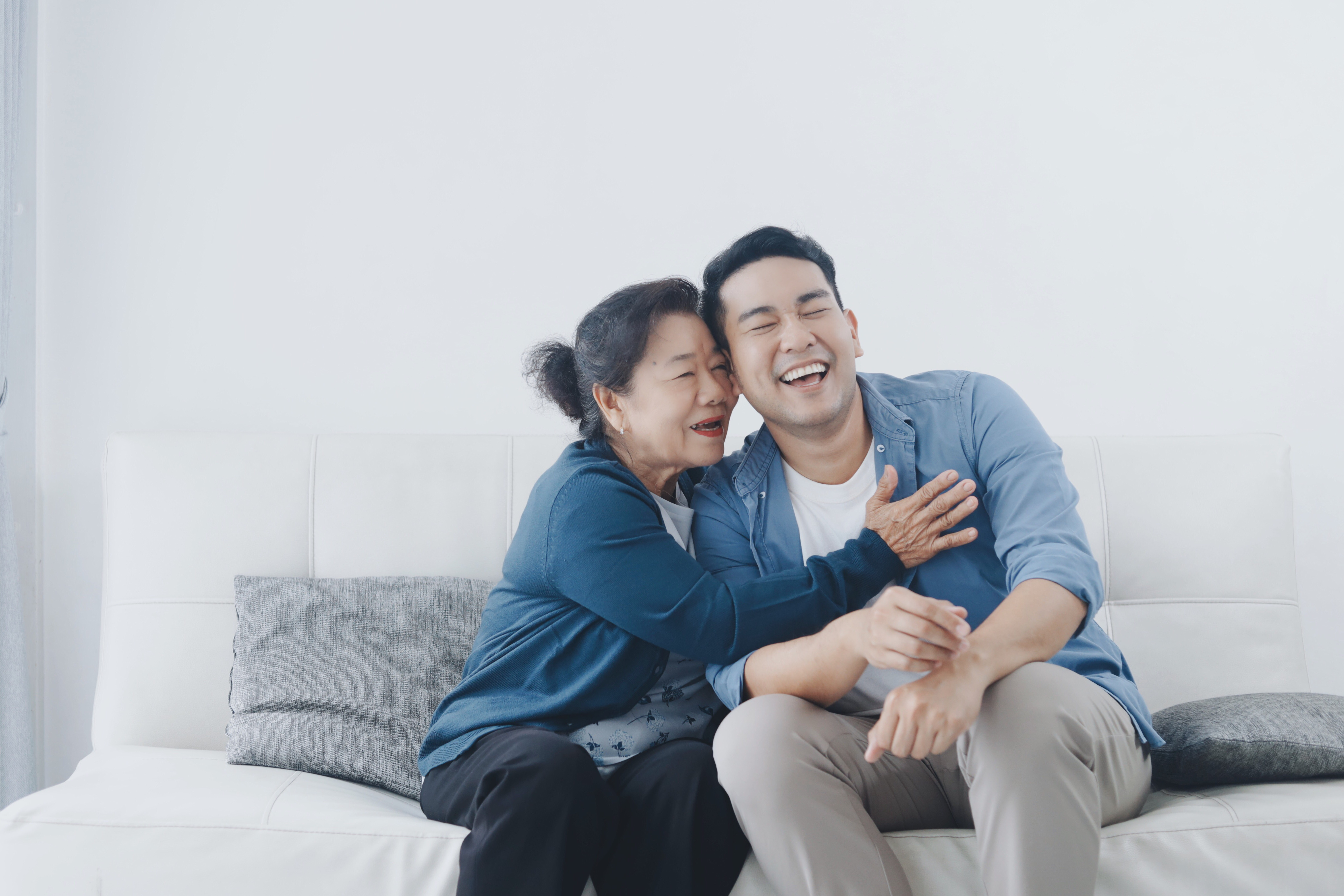 A happy senior Asian woman hugging her son | Source: Shutterstock