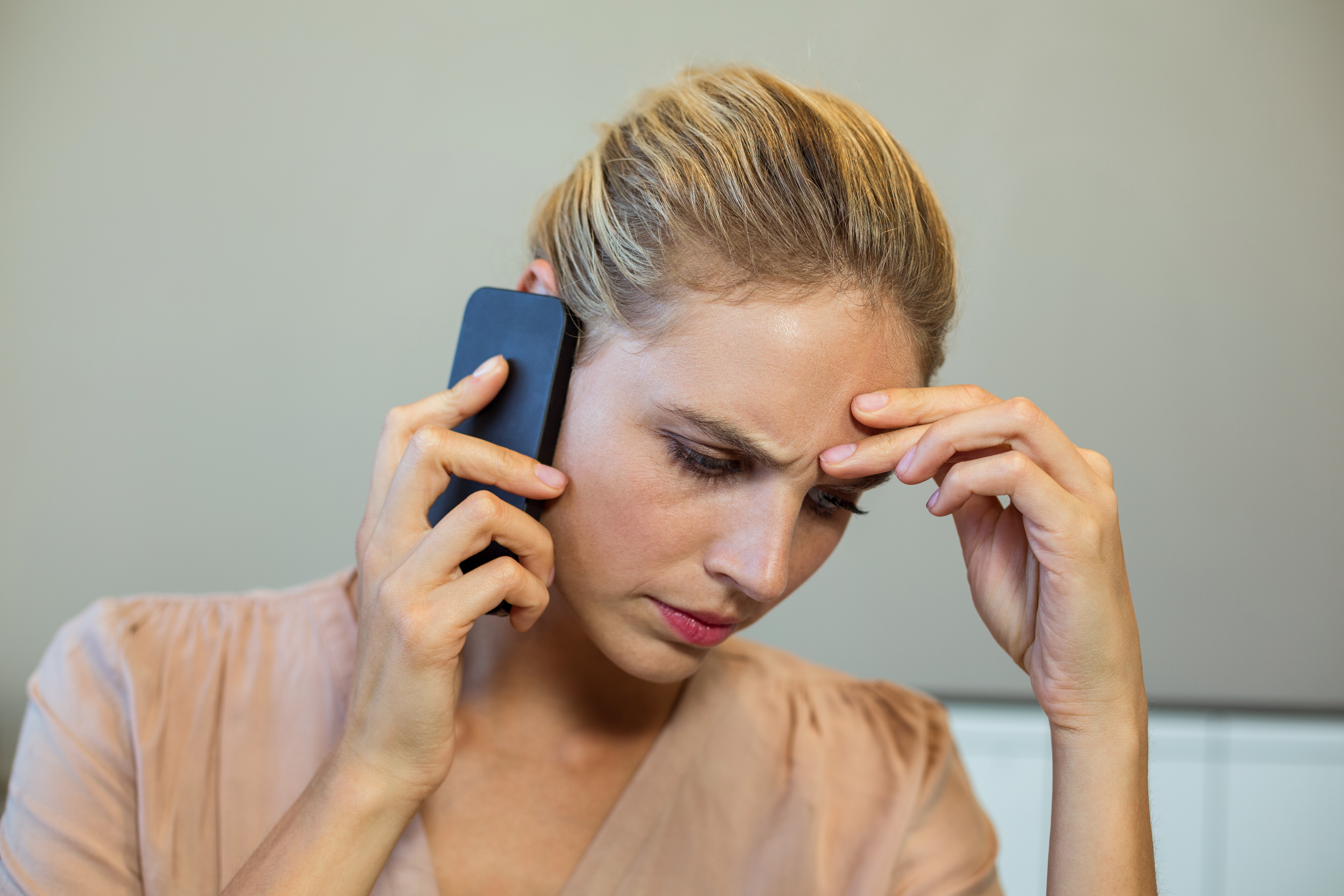 A woman looking concerned while on the phone | Source: Shutterstock