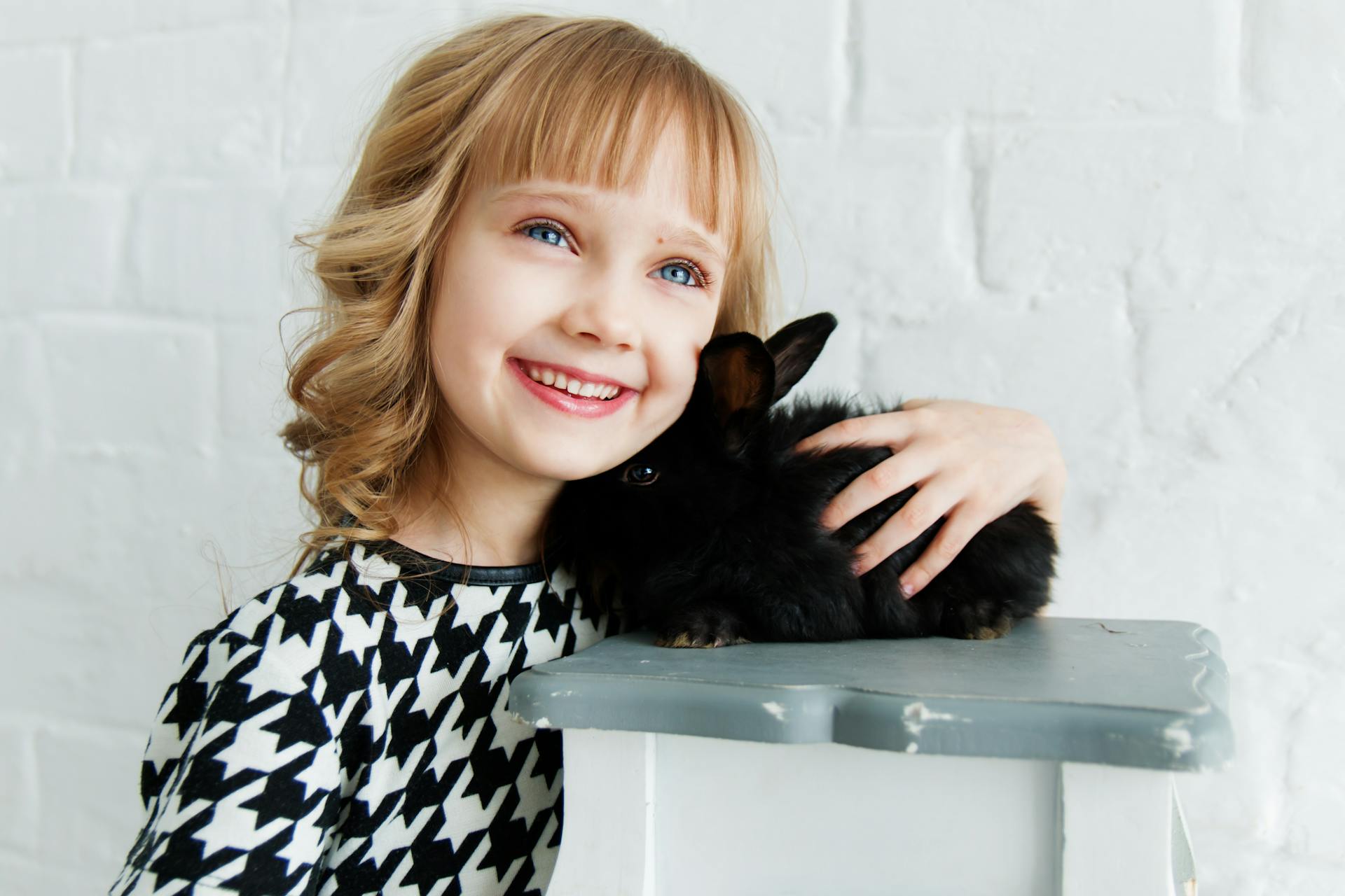A smiling child holding a rabbit | Source: Pexels