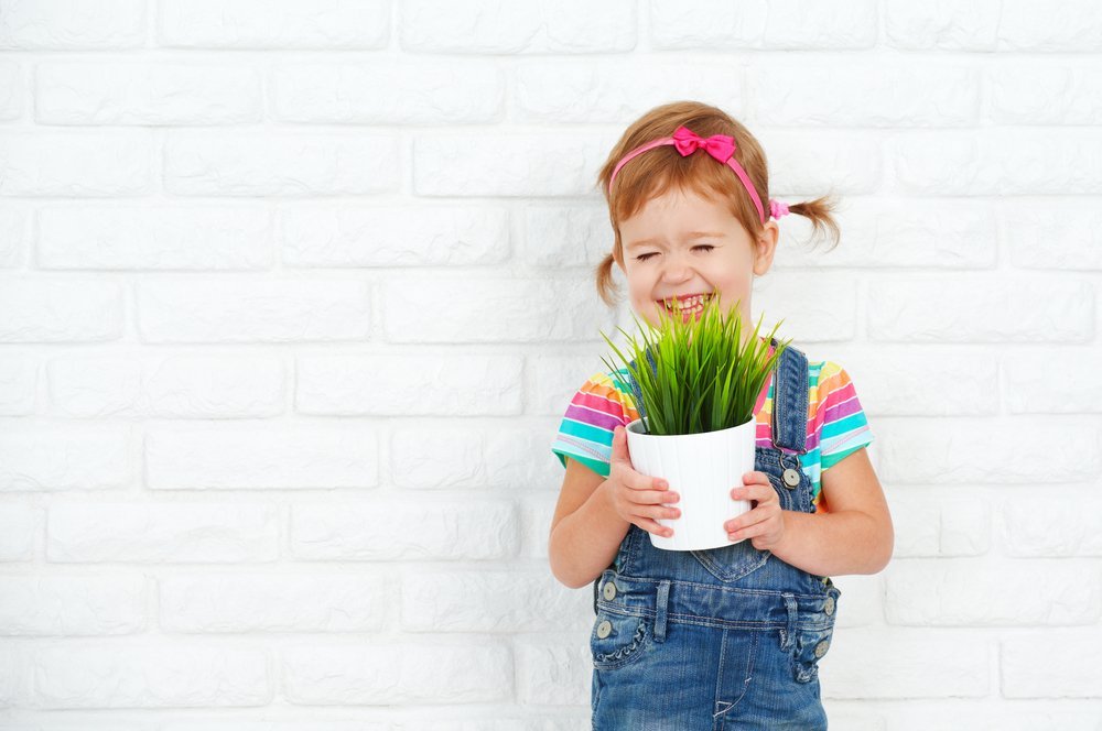 Happy girl holding a potted plant. | Photo: Shutterstock