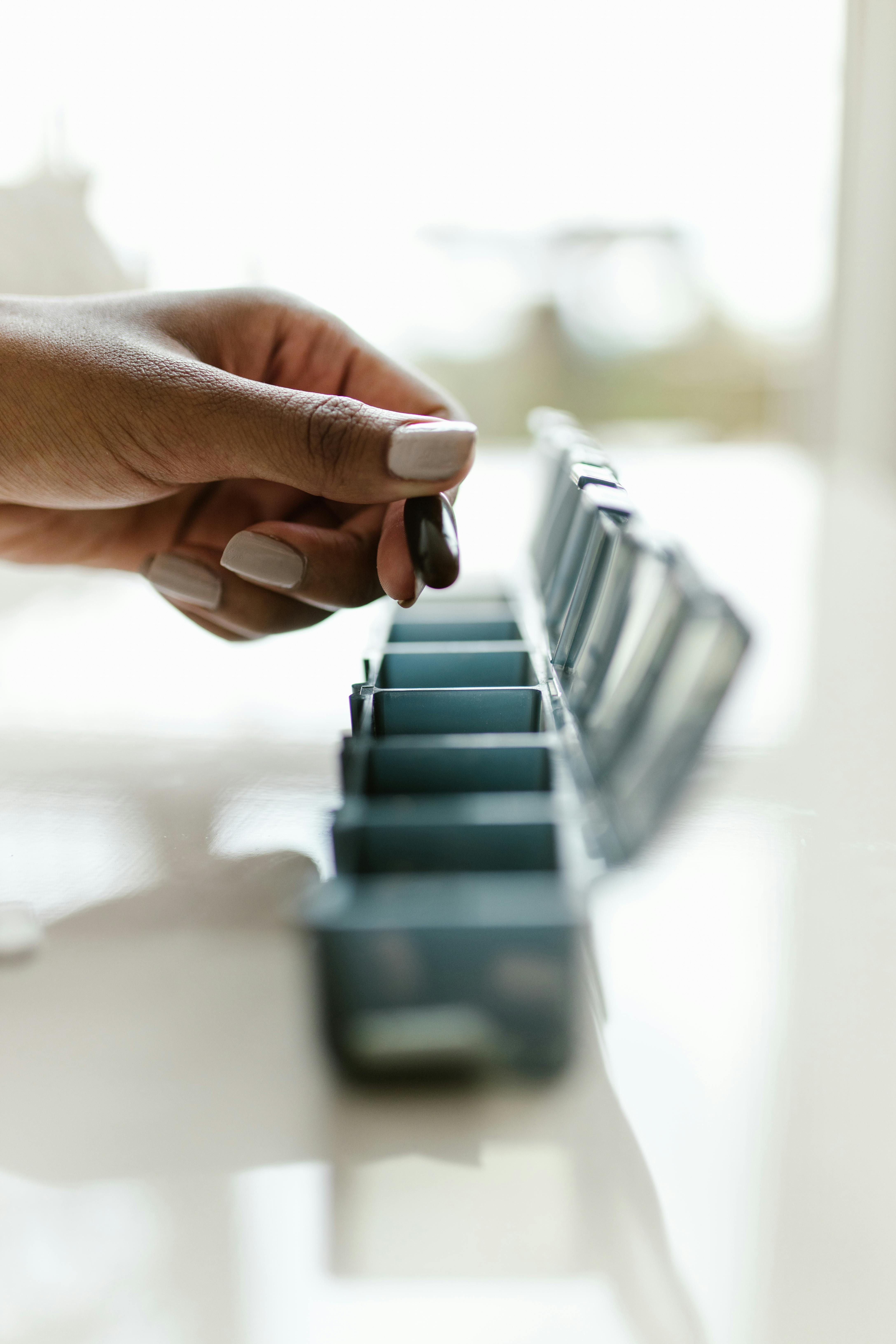 A woman taking a capsule from a pill box | Source: Pexels