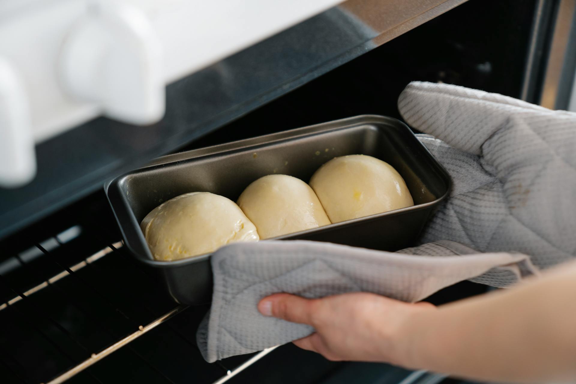 A person putting a tray of bread in the oven | Source: Pexels