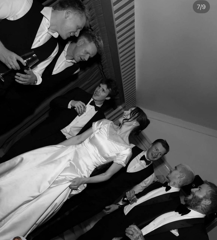 Captured in black and white, Holly Ramsay was seen laughing with the men in her family, as well as David Beckham, his sons, and Adam Peaty. Surrounded by tuxedo-clad family members and friends and holding up her skirt in motion, she appeared relaxed and radiant, her dress catching the light even without colour. The candid moment highlighted the warmth and ease of the celebration's later hours. | Source: Instagram/britishvogue