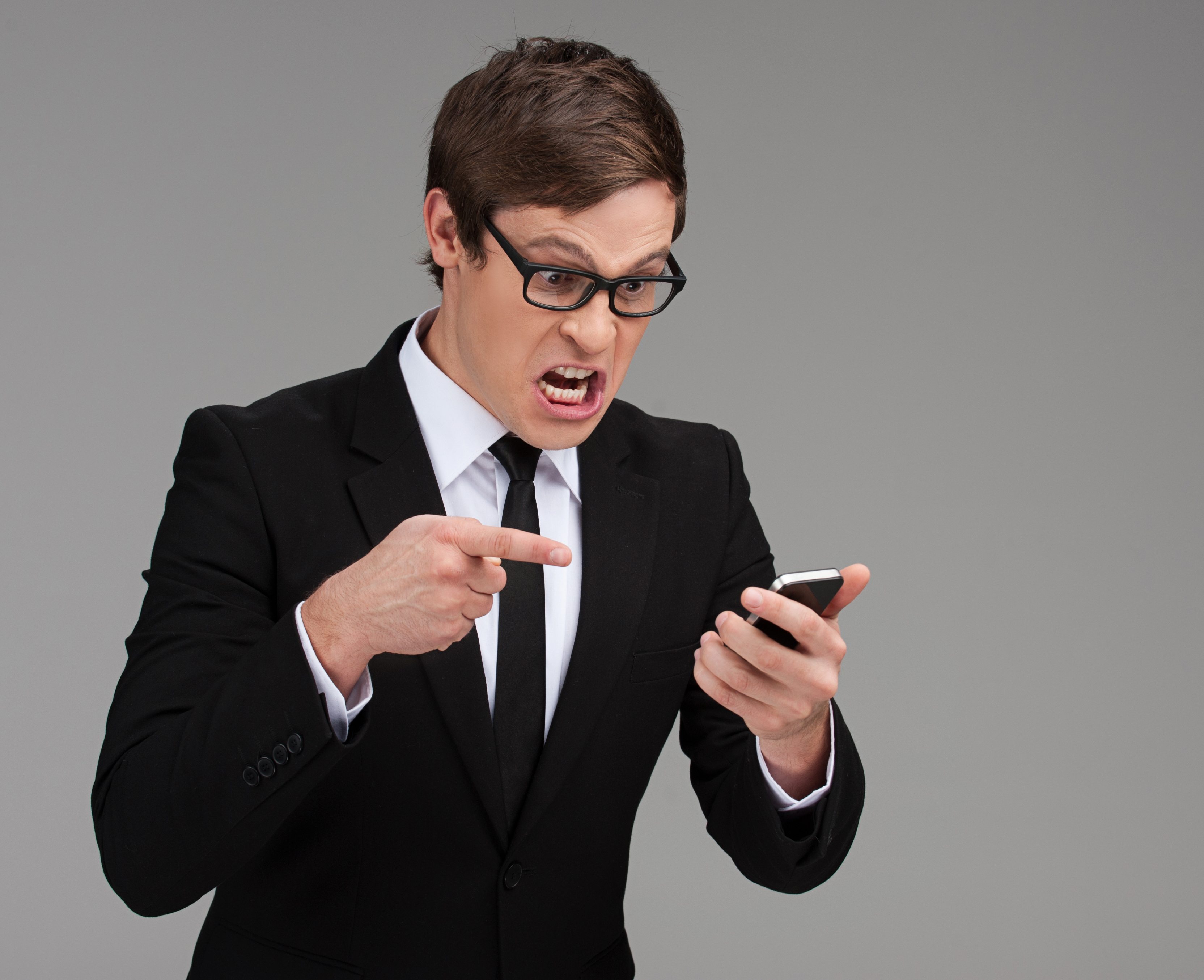 An angry man shouting at a phone | Source: Shutterstock