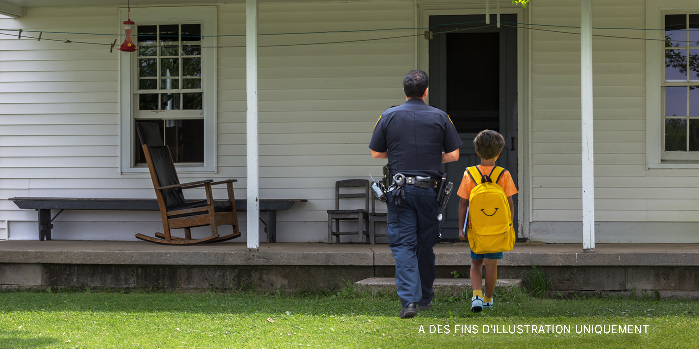 Un jeune garçon et un policier se dirigent vers une maison | Source : Shutterstock