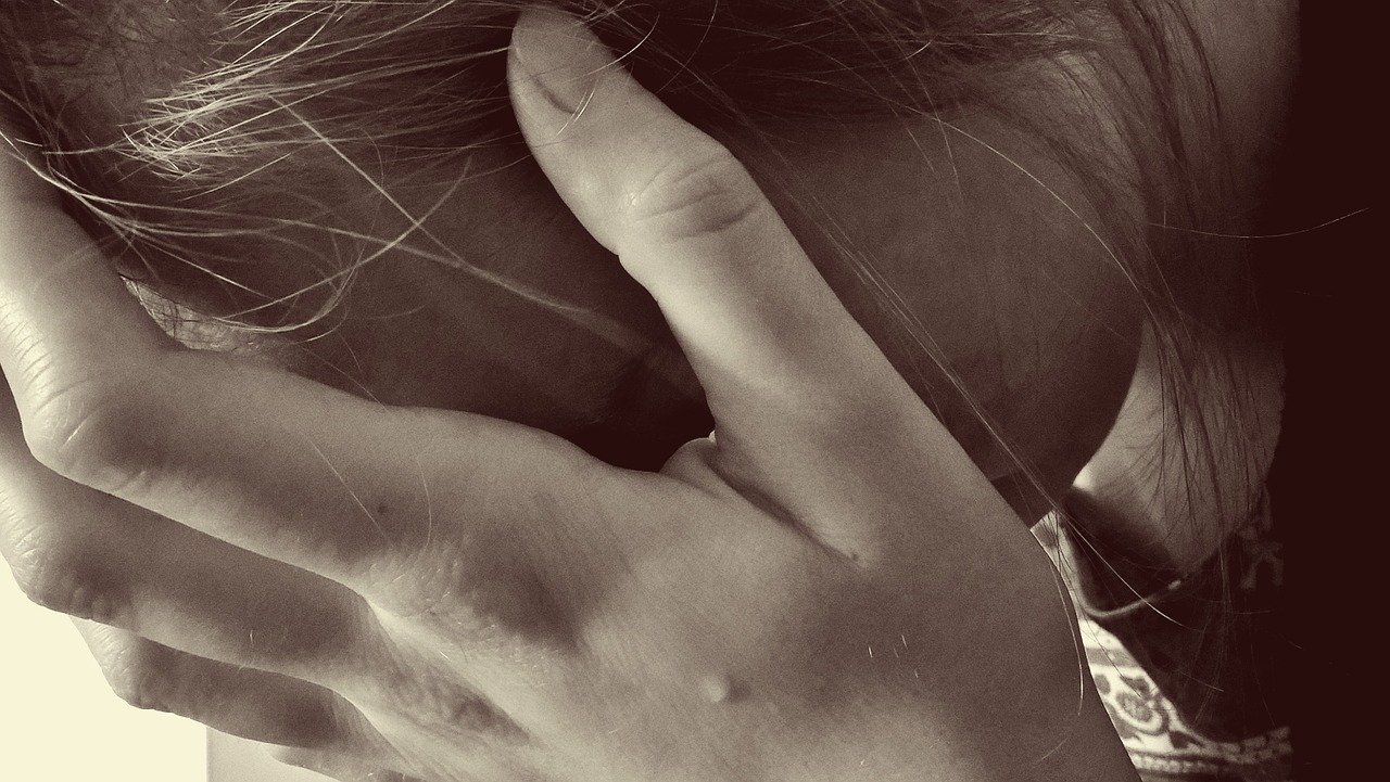Woman holding her head in her hands. Image credit: Pixabay