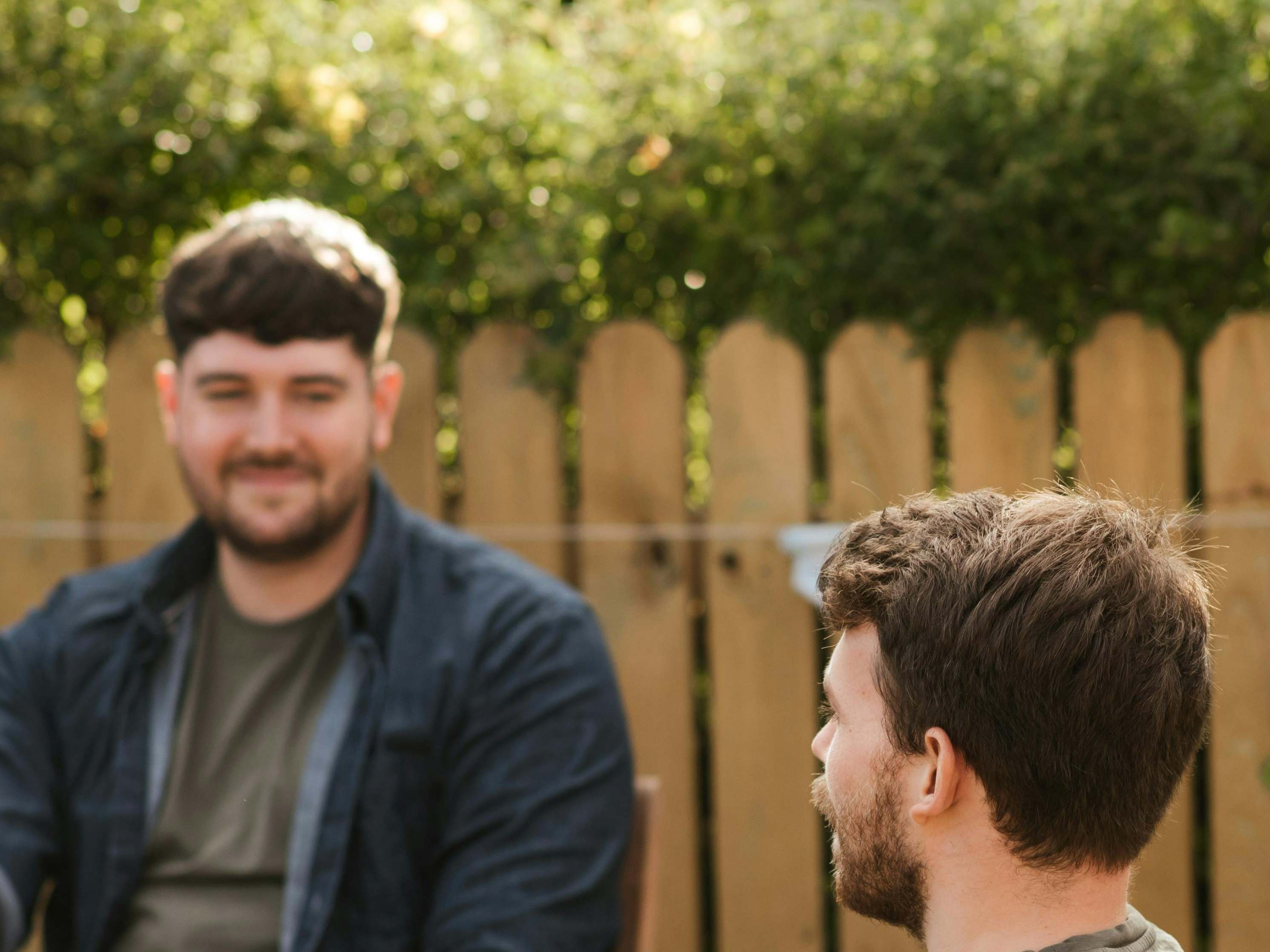 Two men in front of a wooden fence | Source: Pexels