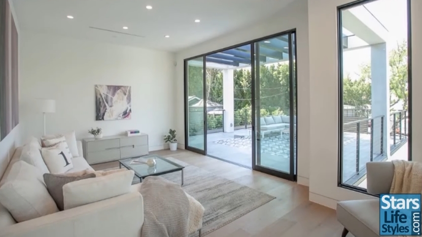 One of the home's bright living spaces opens onto an upstairs outdoor lounge area. | Source: YouTube/Stars Lifestyles
