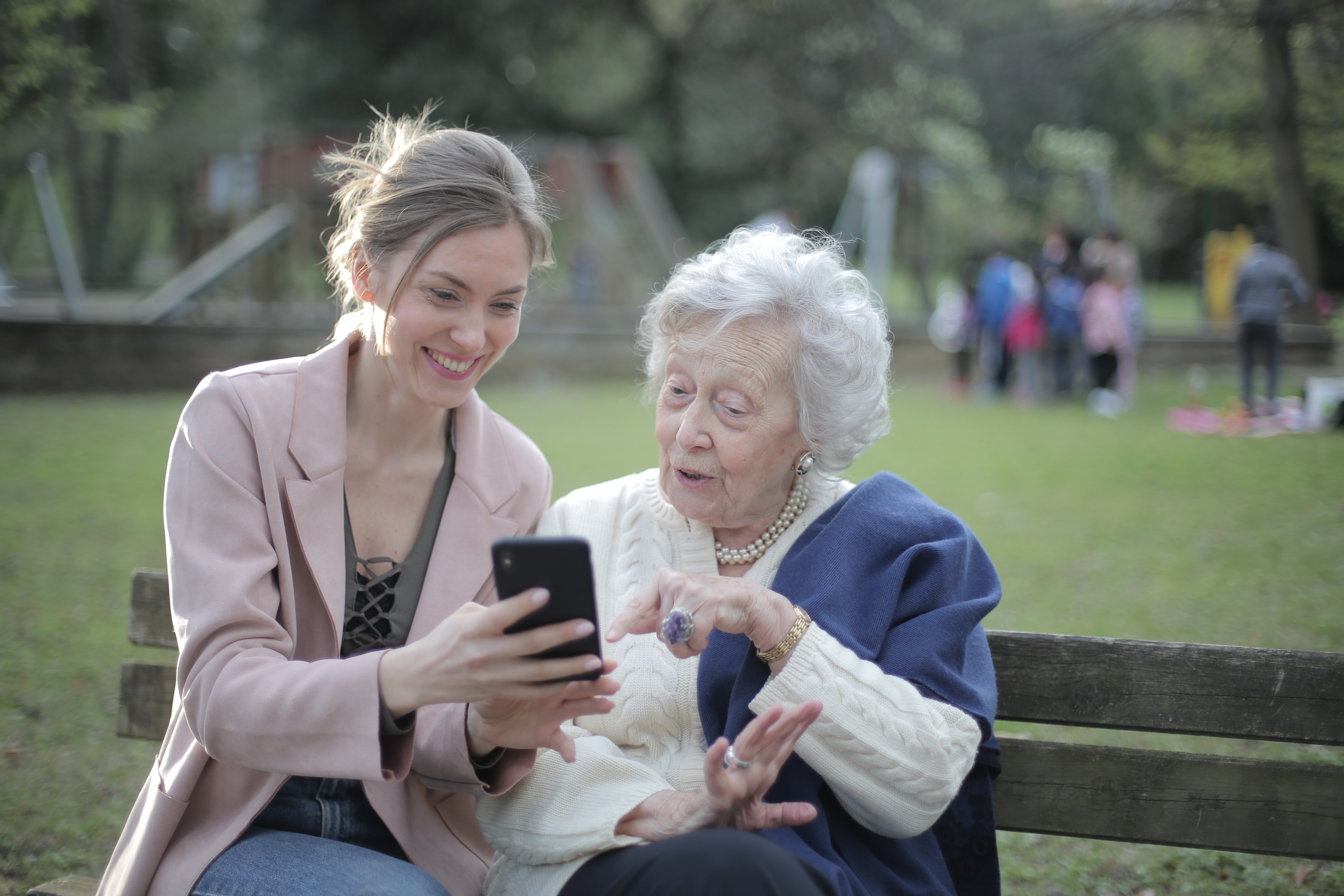An elderly woman sitting with a young lady holding a phone in her hand. | Photo: Pexels