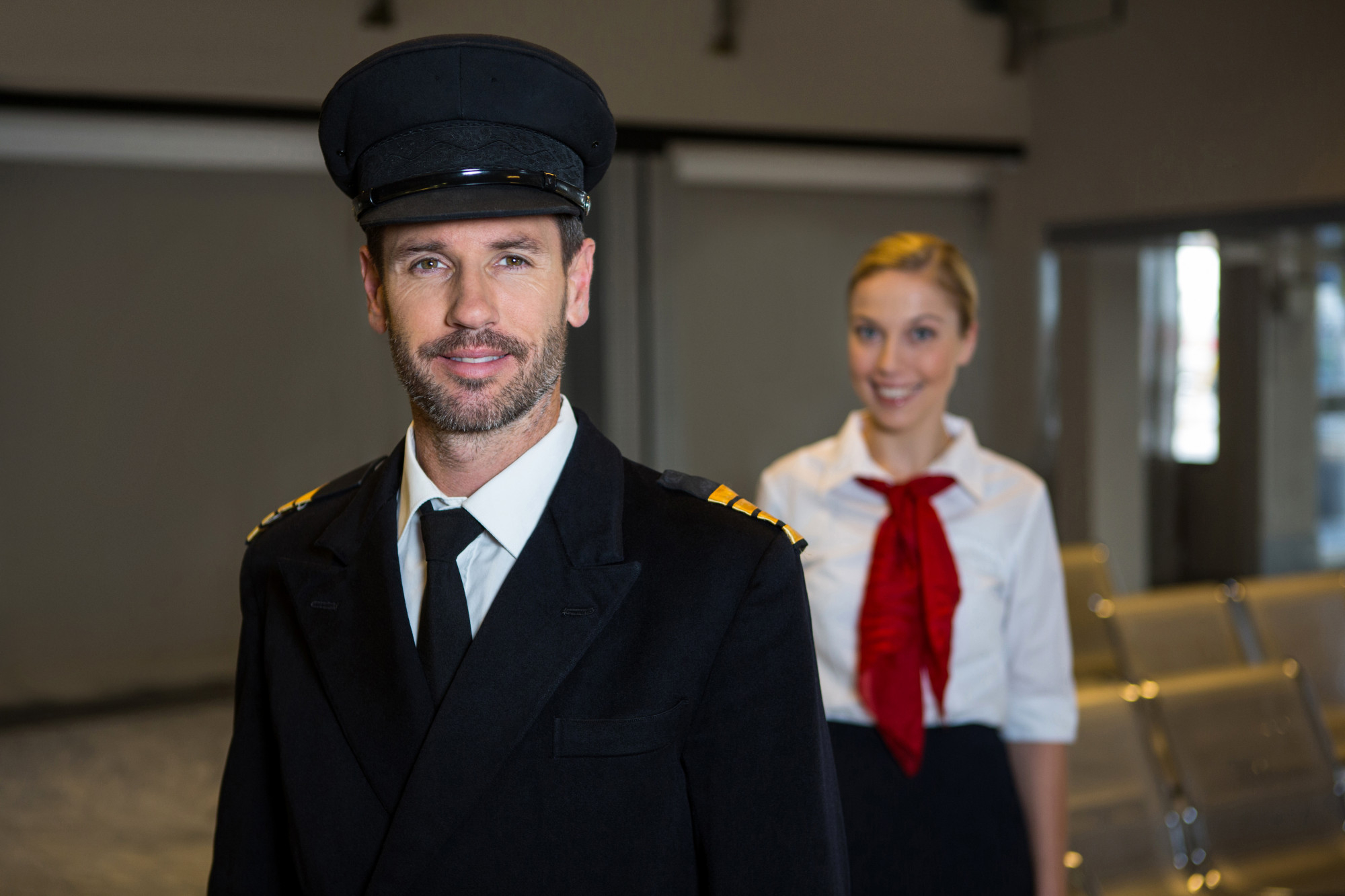 A pilot standing in front of a stewardess | Source: Freepik