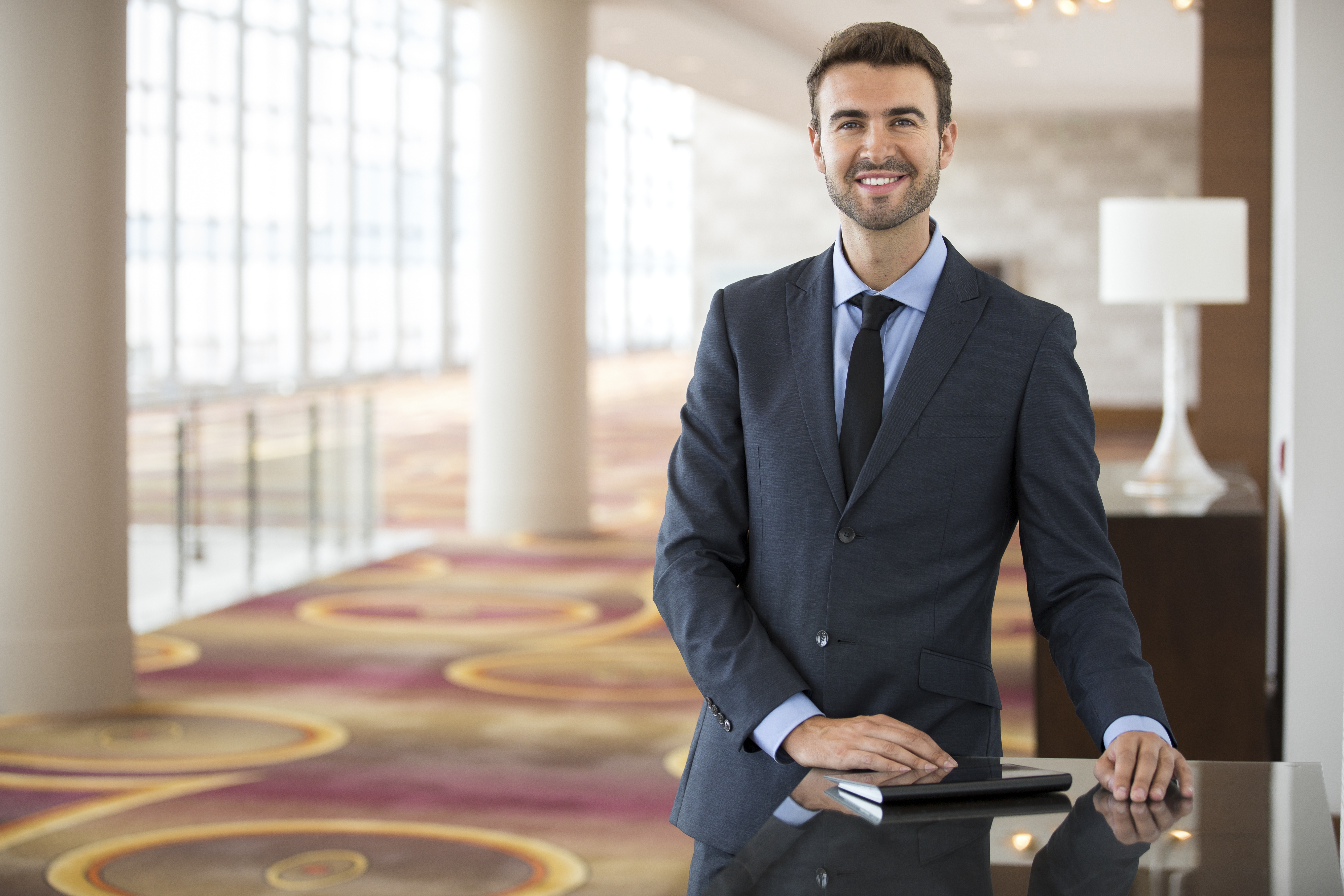 Hotel manager staring at the camera in a hotel lobby. | Source: Shutterstock