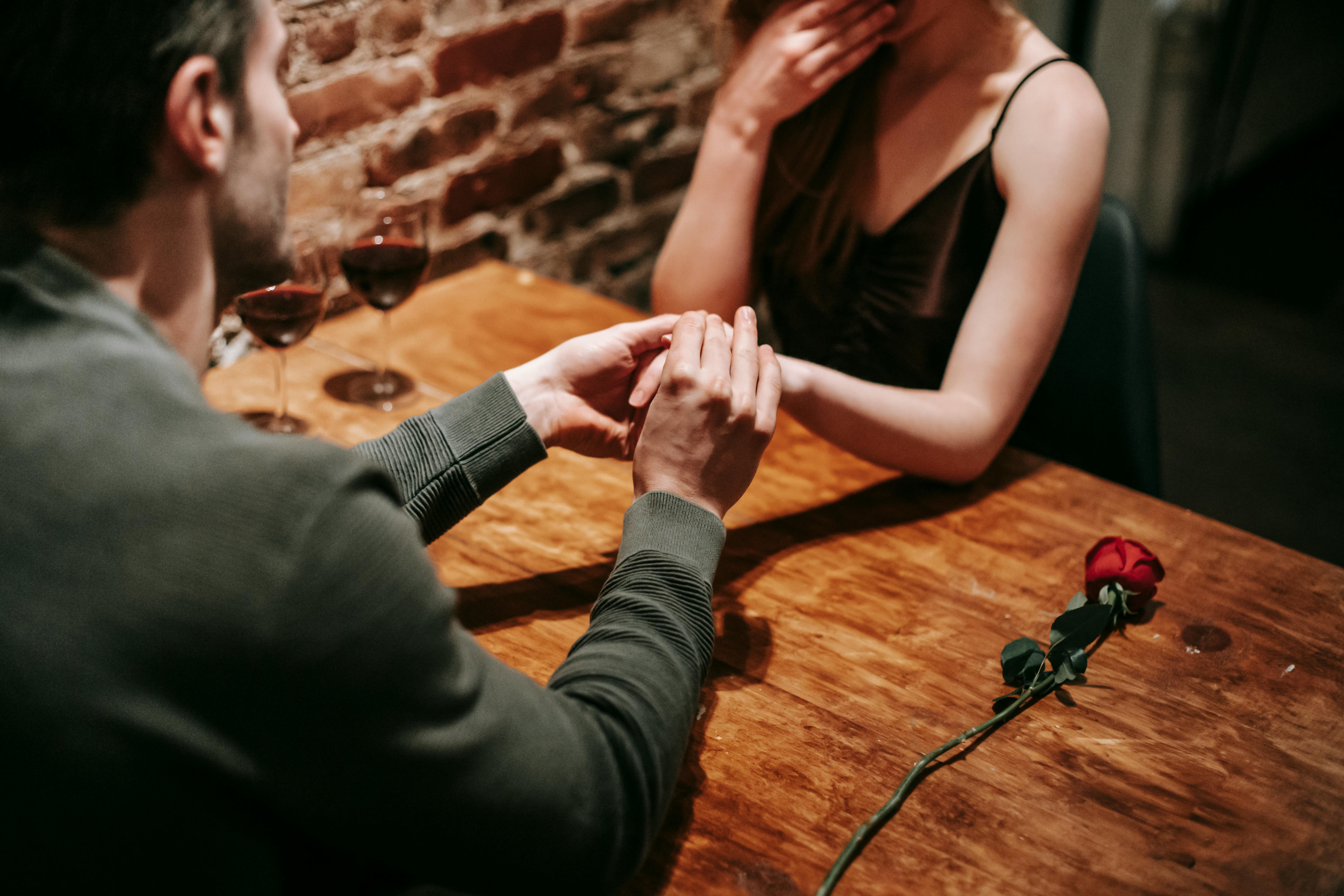 A man holding the hand of his partner at a restaurant | Source: Pexels