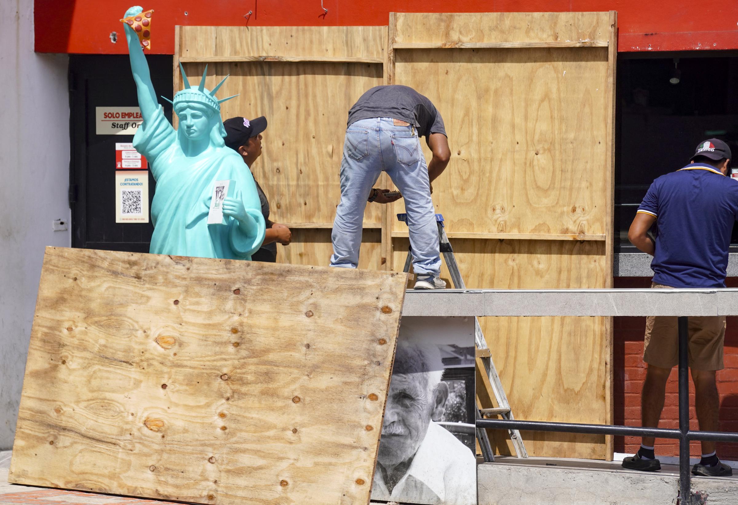 Workers place sheets of wood over windows and glass doors to protect them from the strong winds expected with the arrival of Hurricane Milton in Mexico, on October 7, 2024 | Source: Getty Images